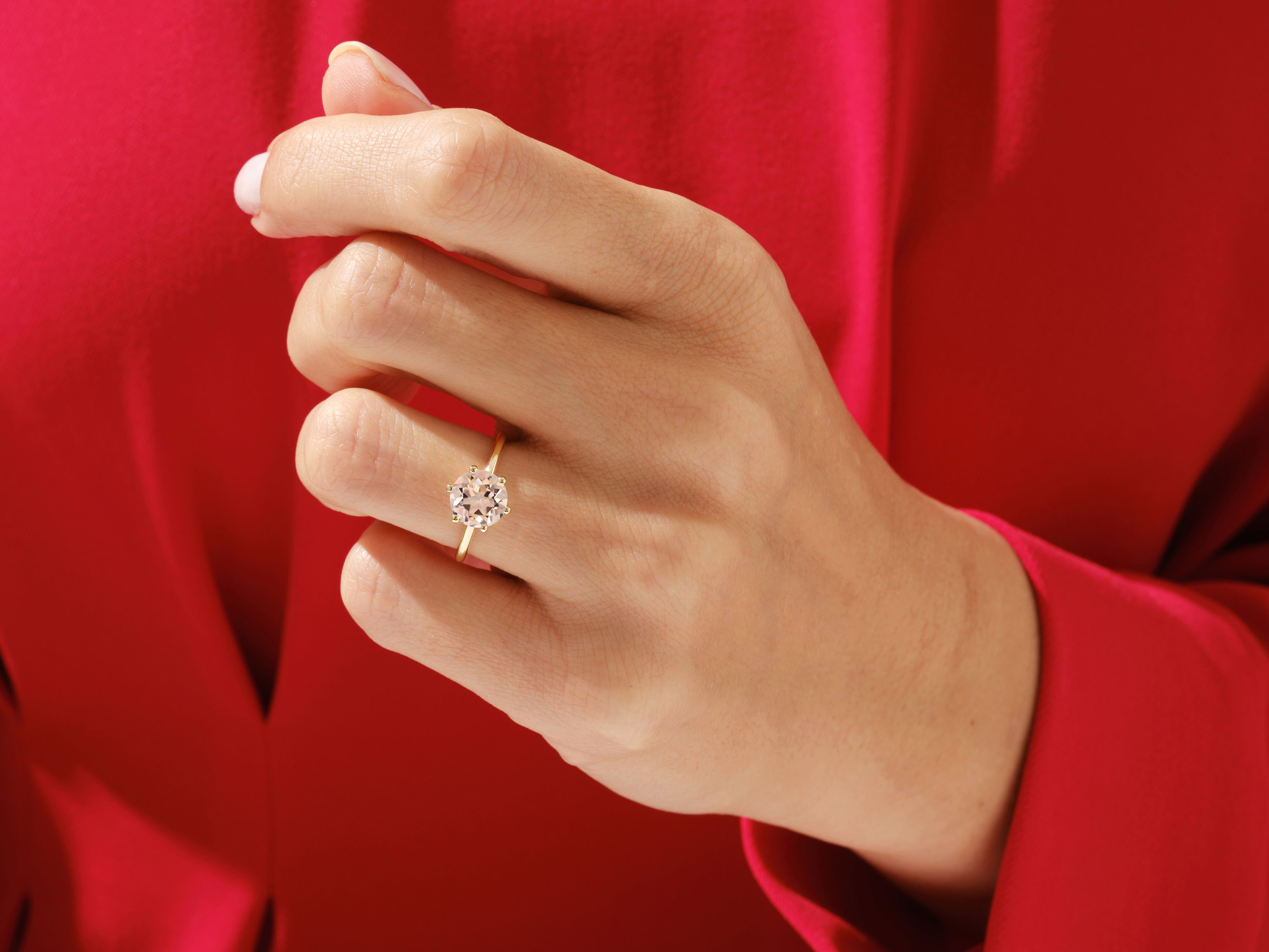Gold ring with a light pink gemstone on a hand