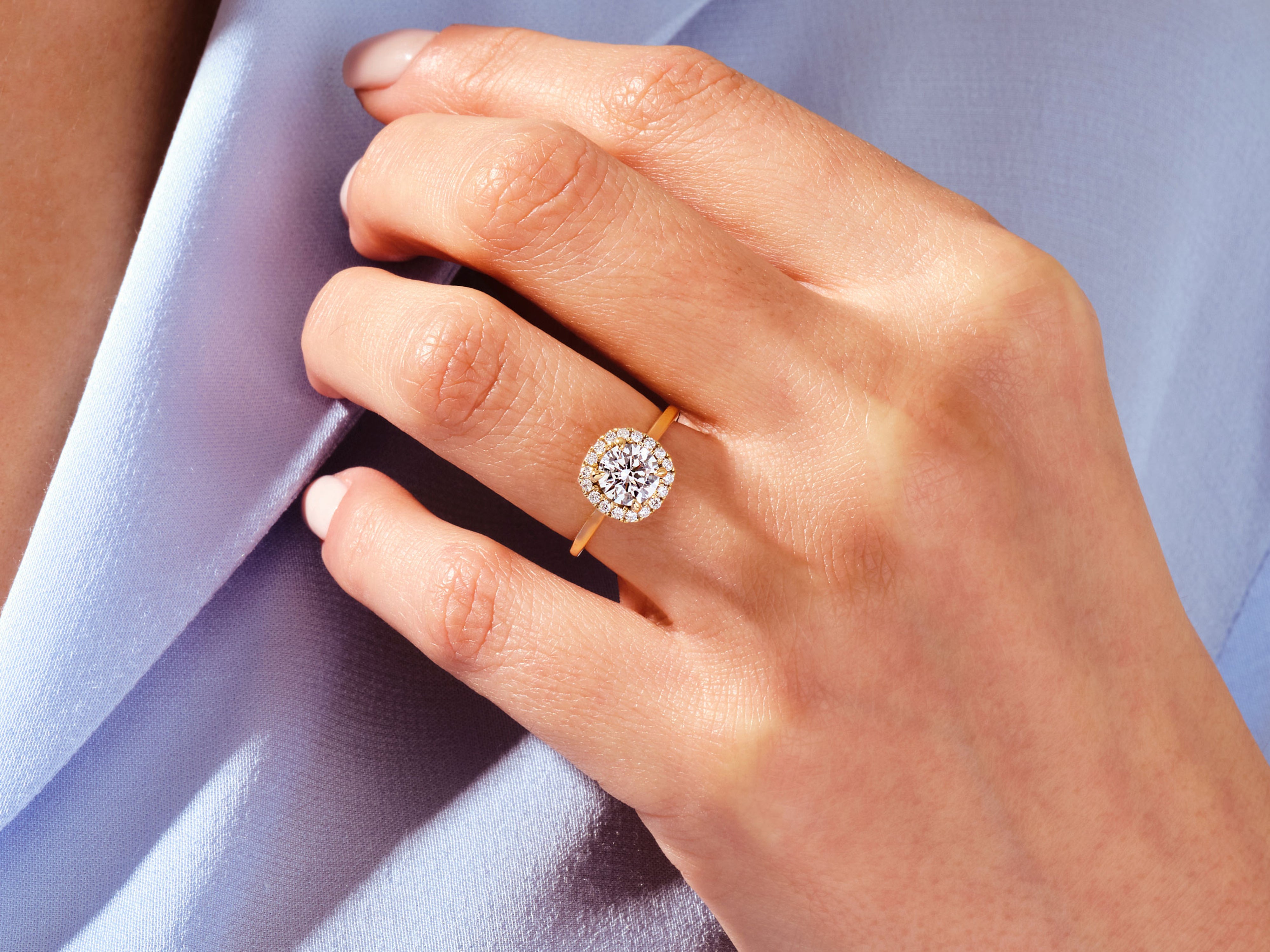Gold diamond halo engagement ring on hand