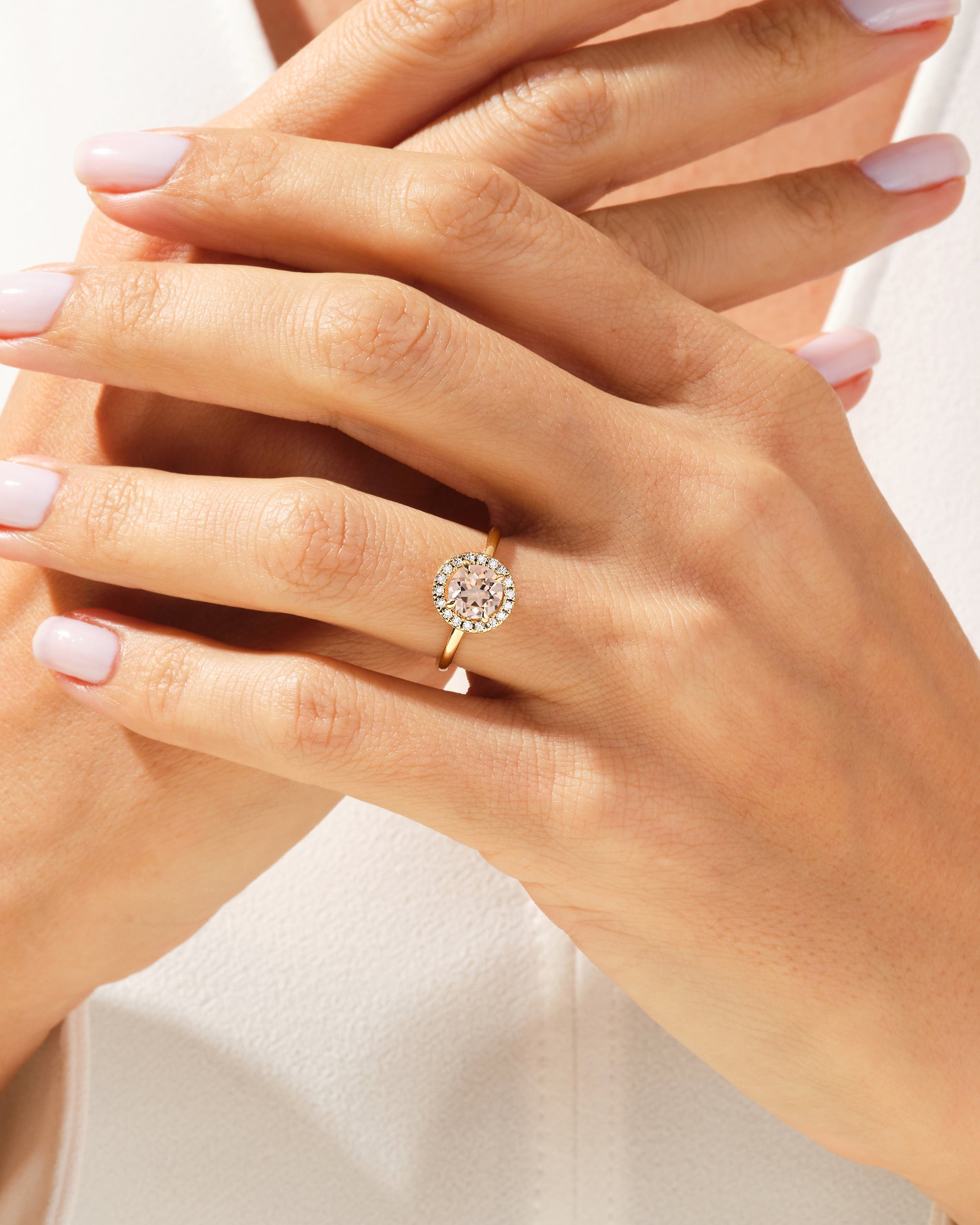 Gold halo ring with a pink center stone and diamonds