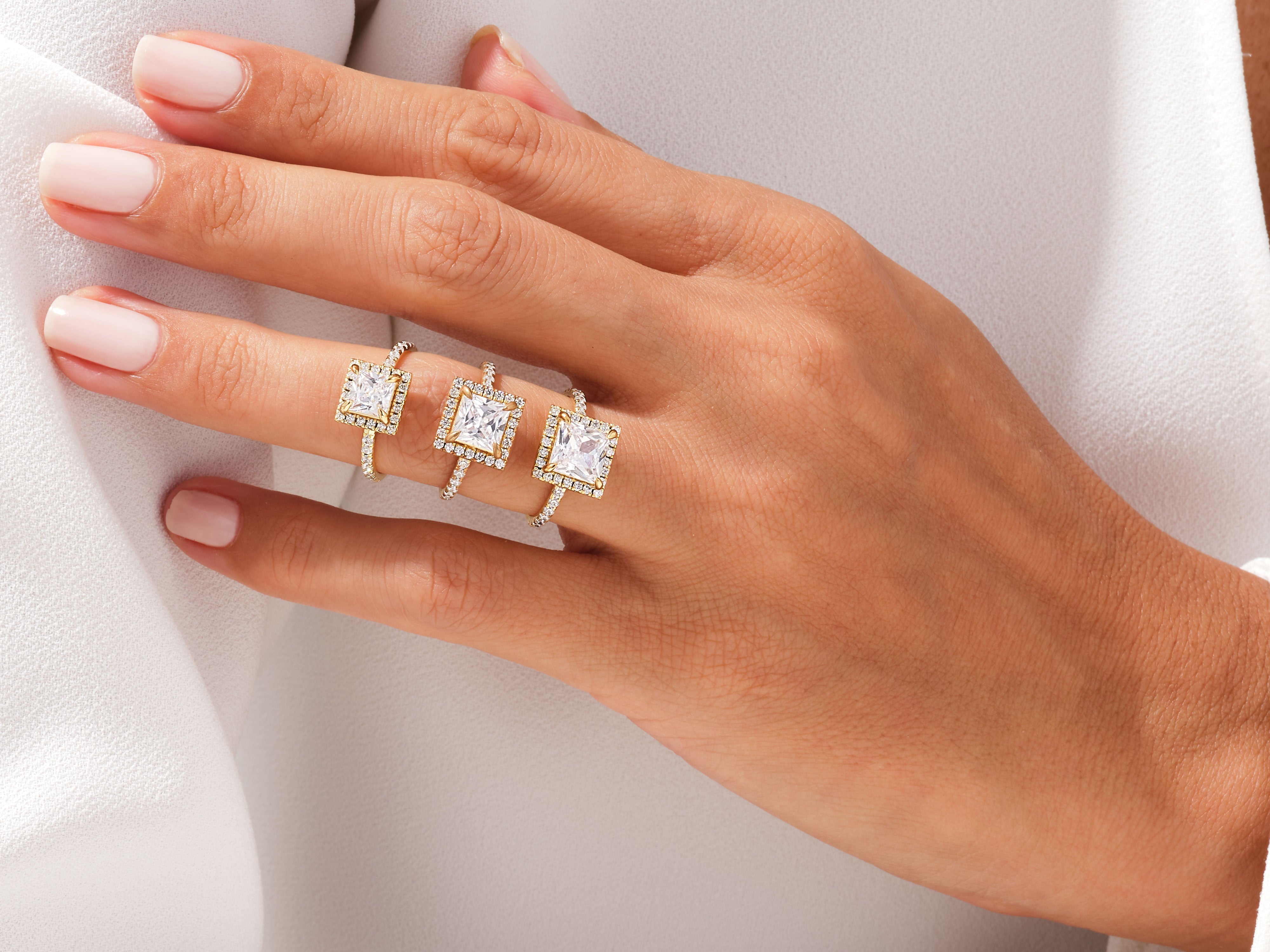 Gold diamond halo square cut engagement rings on hand