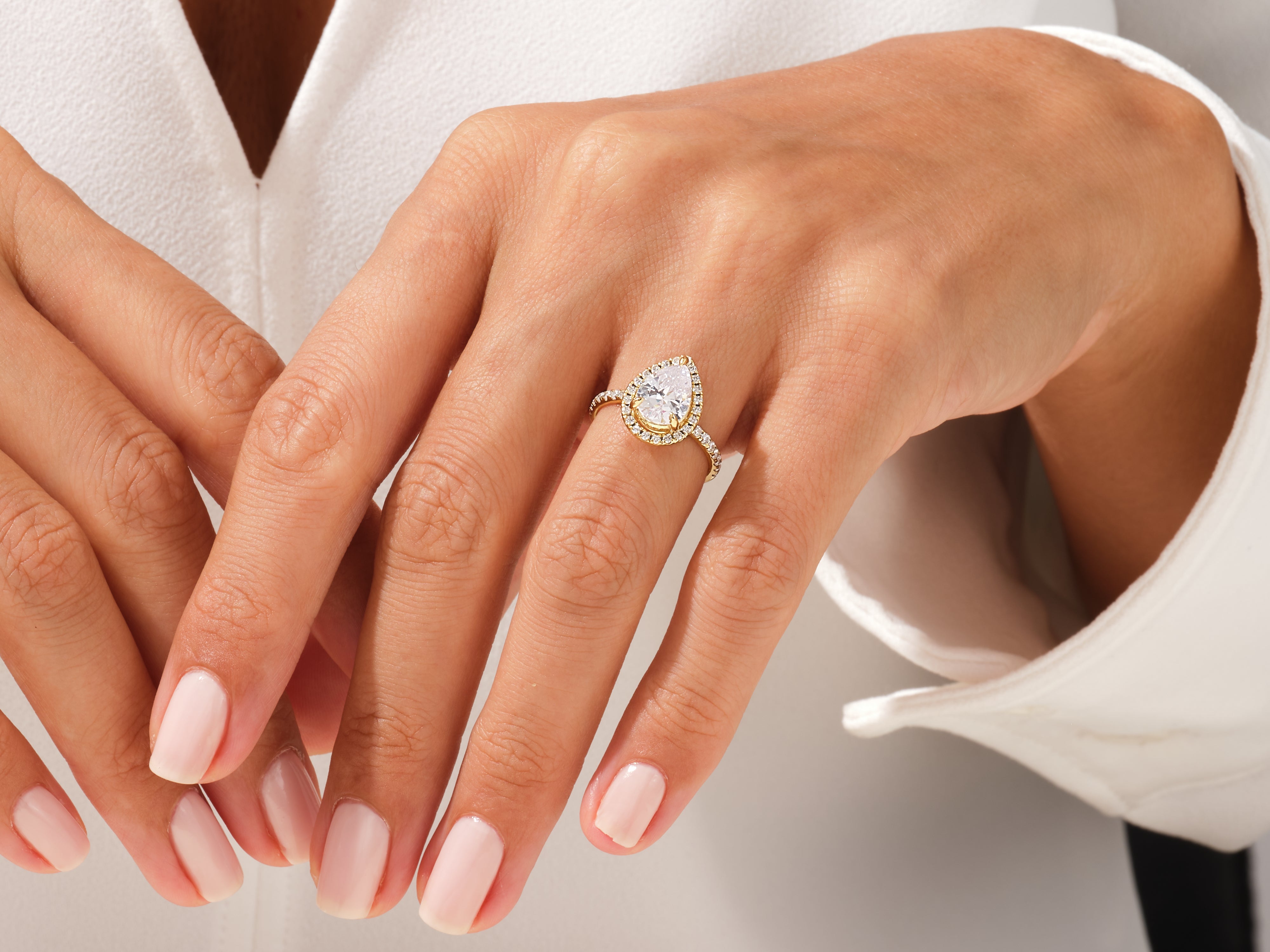 Pear-shaped diamond engagement ring with halo on a woman's hand