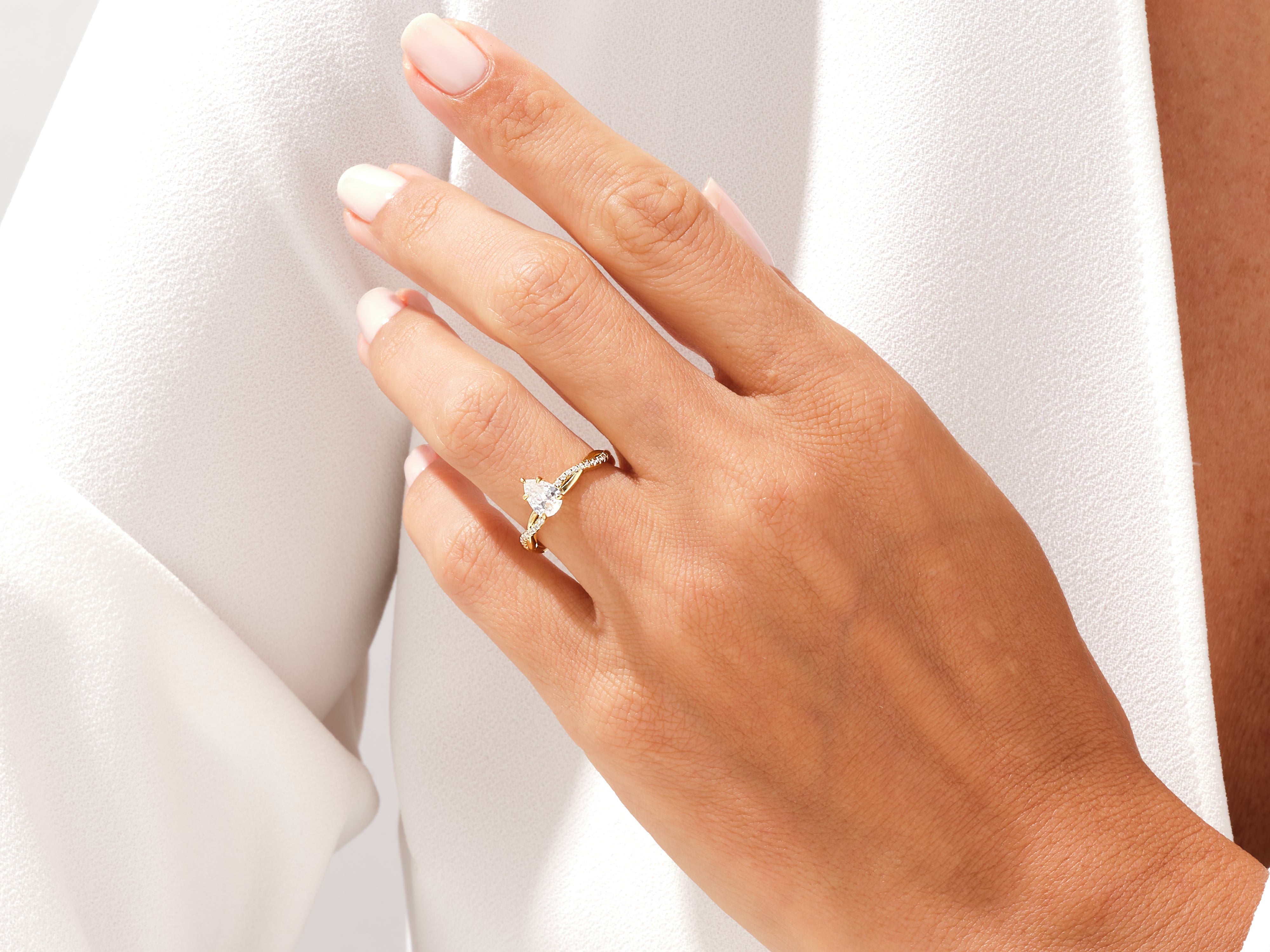 Gold pear-shaped diamond engagement ring on a woman's hand