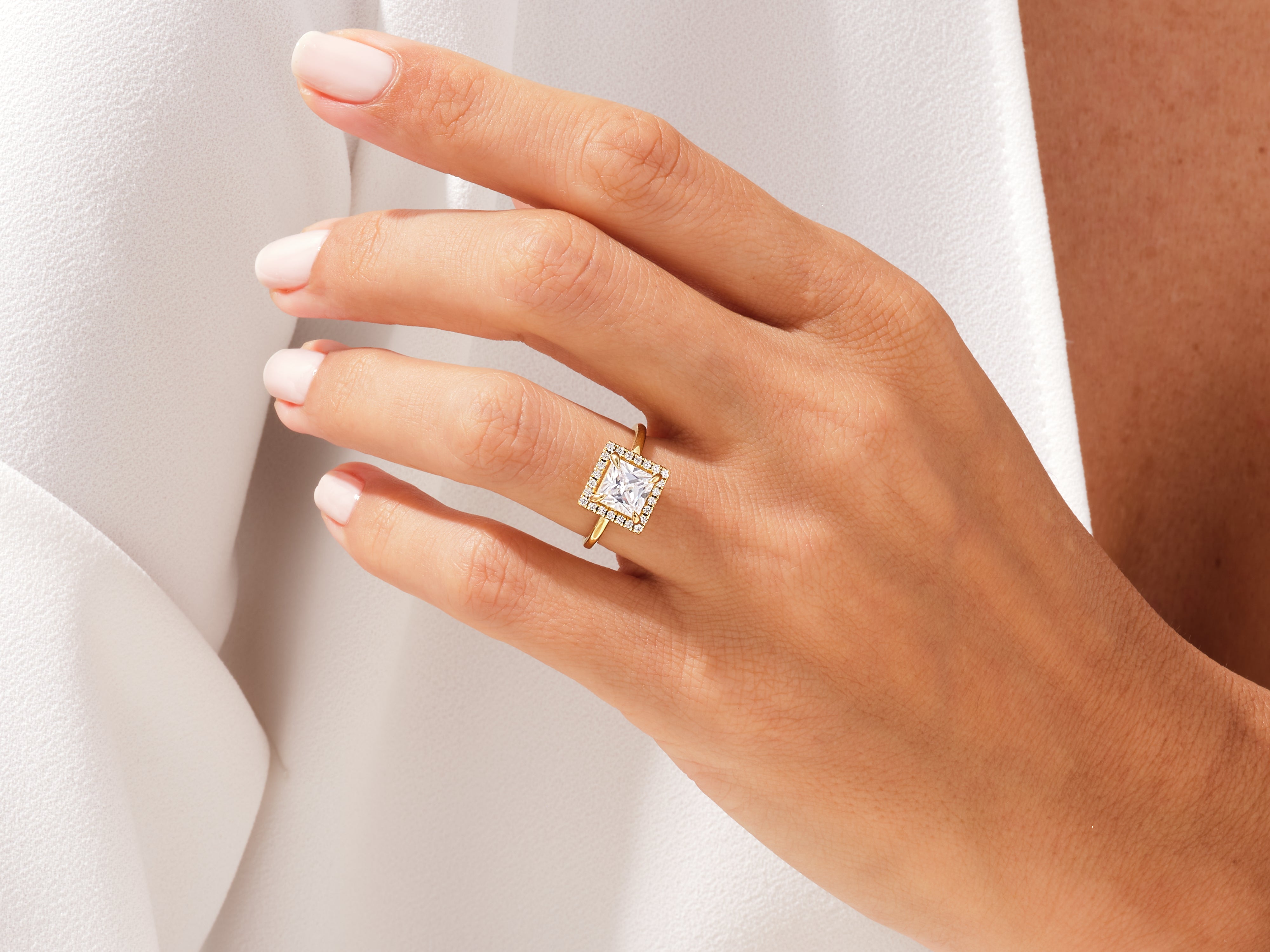 Gold princess cut diamond halo engagement ring on hand