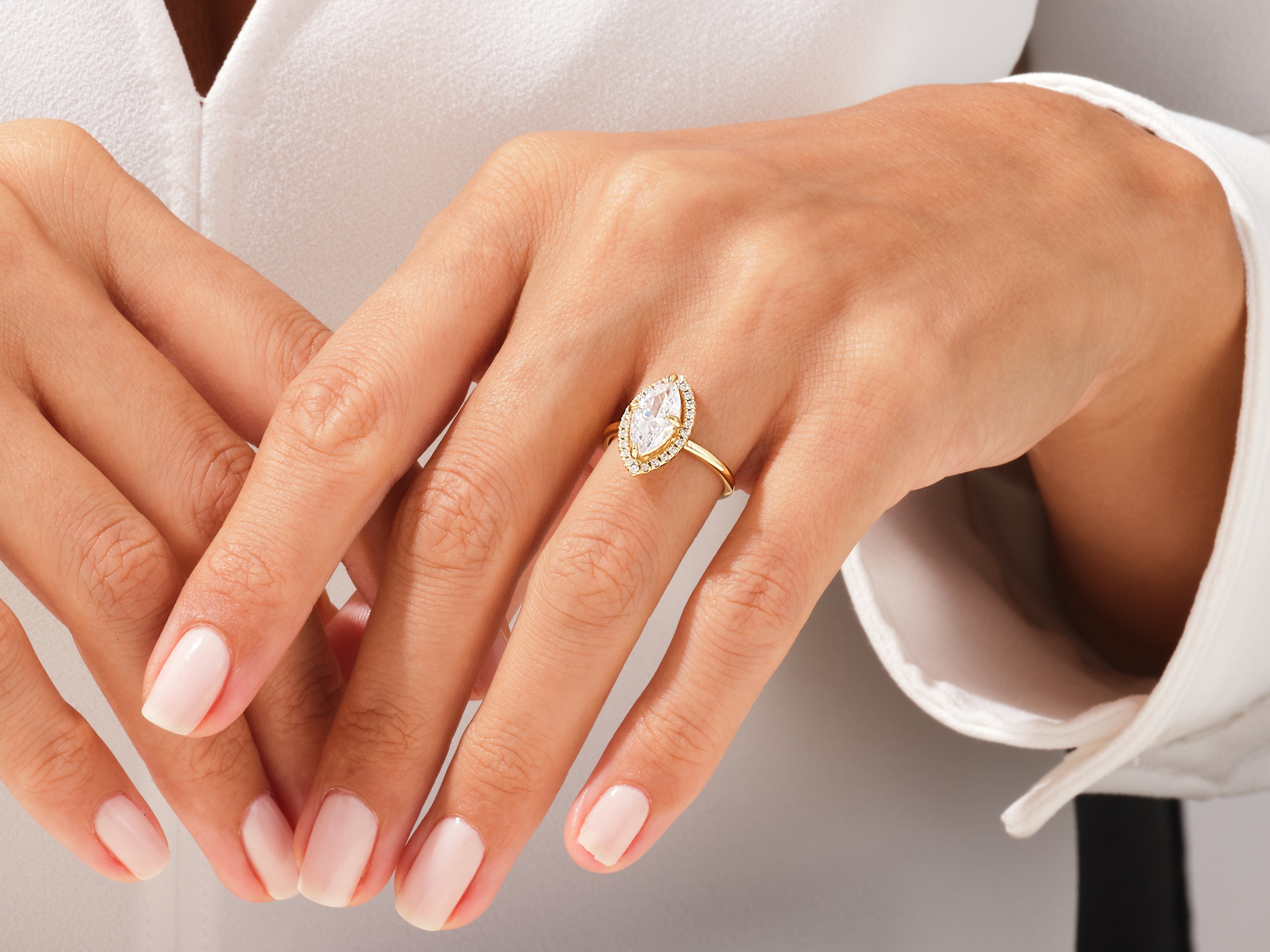 Gold marquise diamond halo engagement ring on a woman's hand