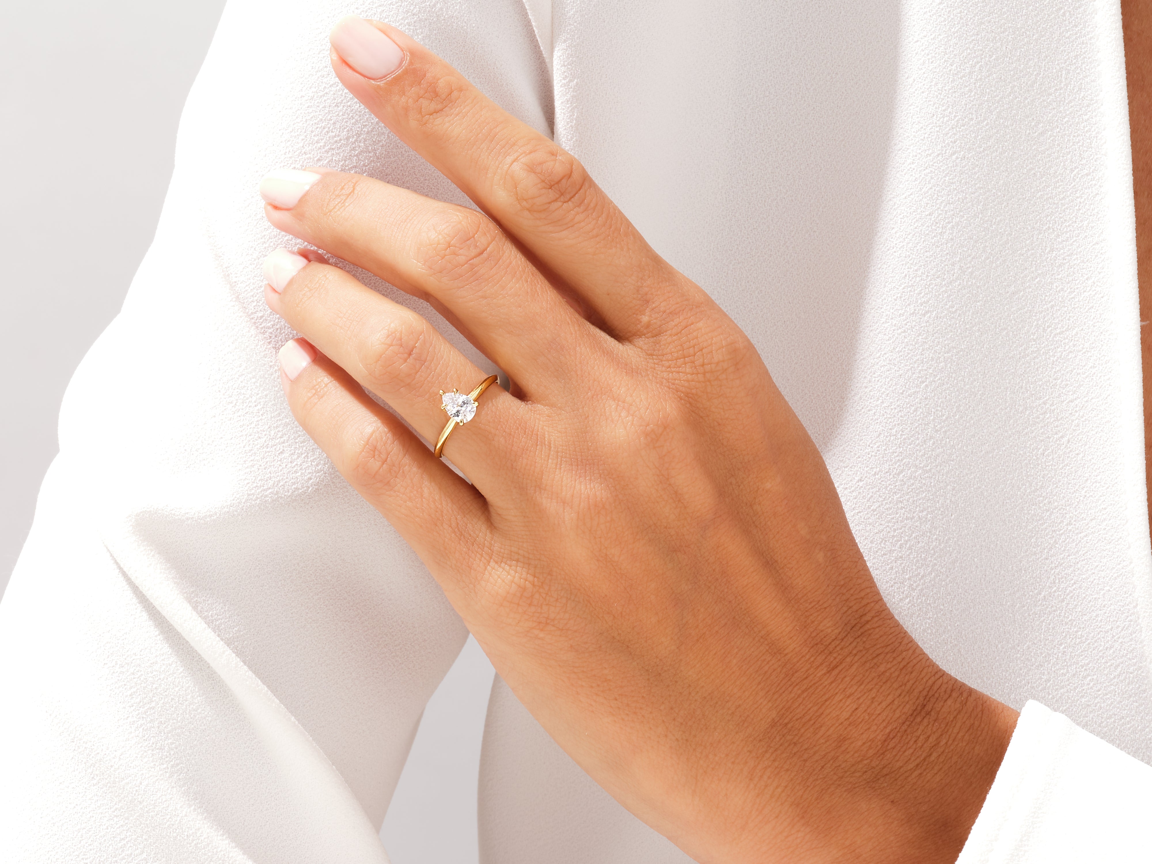 Gold pear-shaped diamond engagement ring on a woman's hand