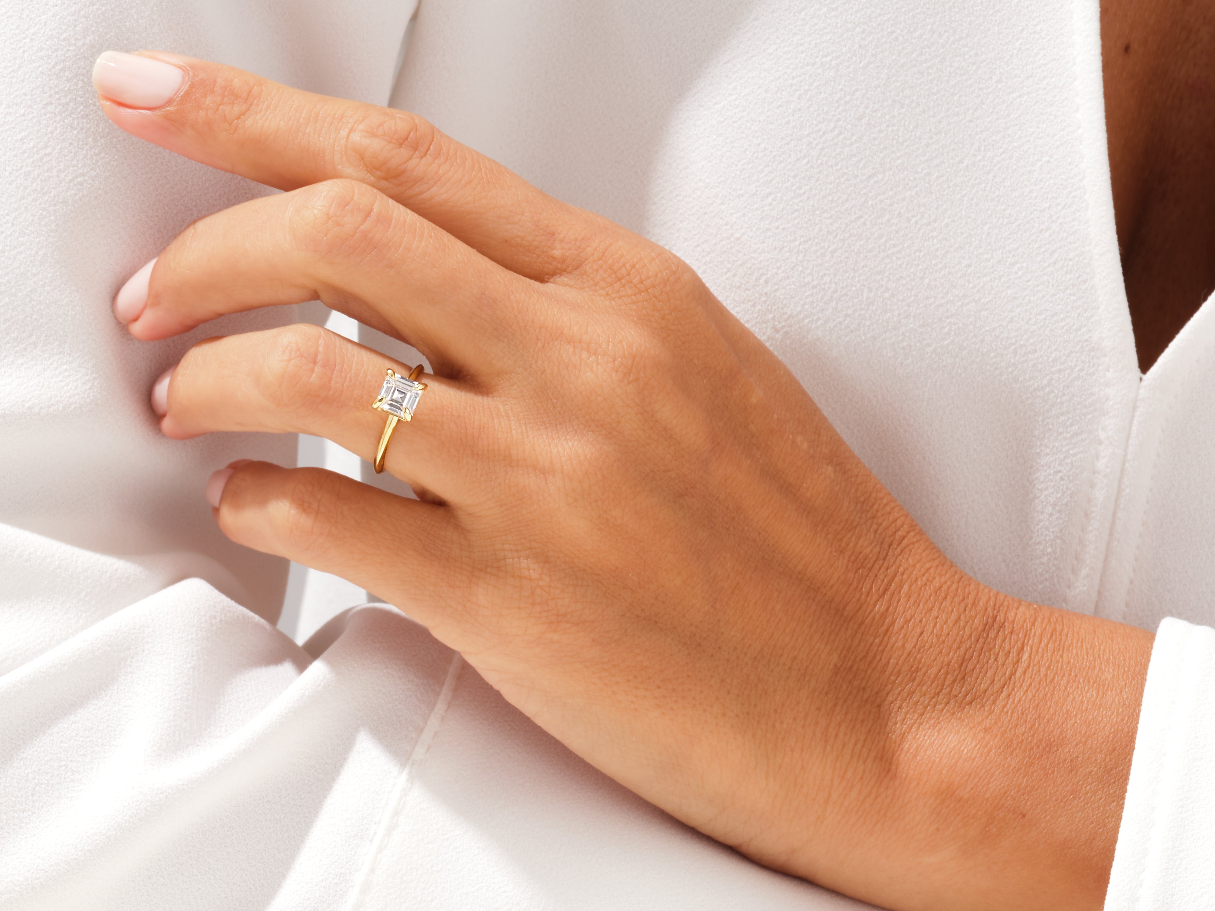 Gold ring with emerald-cut diamond on a woman's hand
