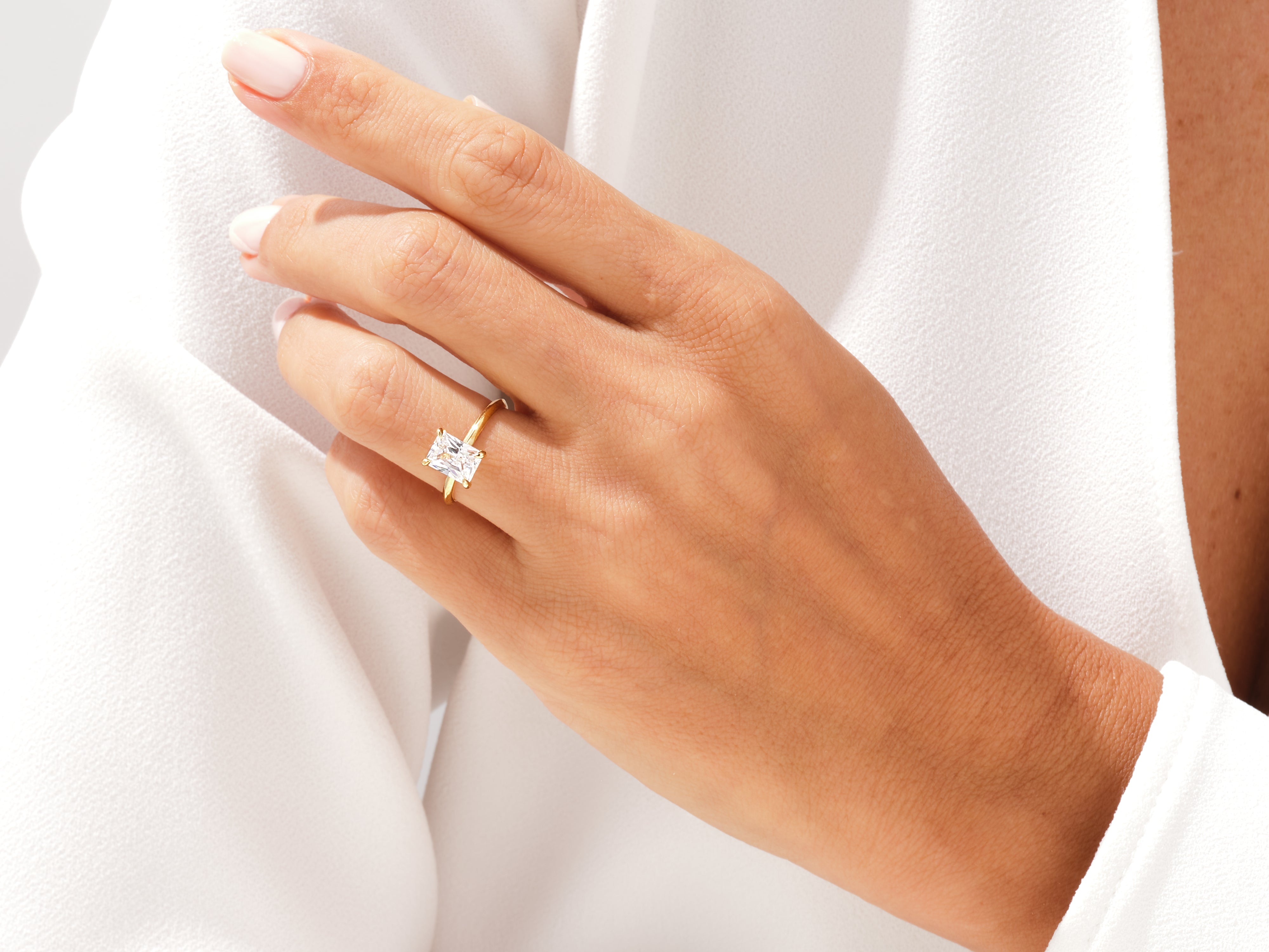Gold ring with emerald cut diamond on a woman's hand