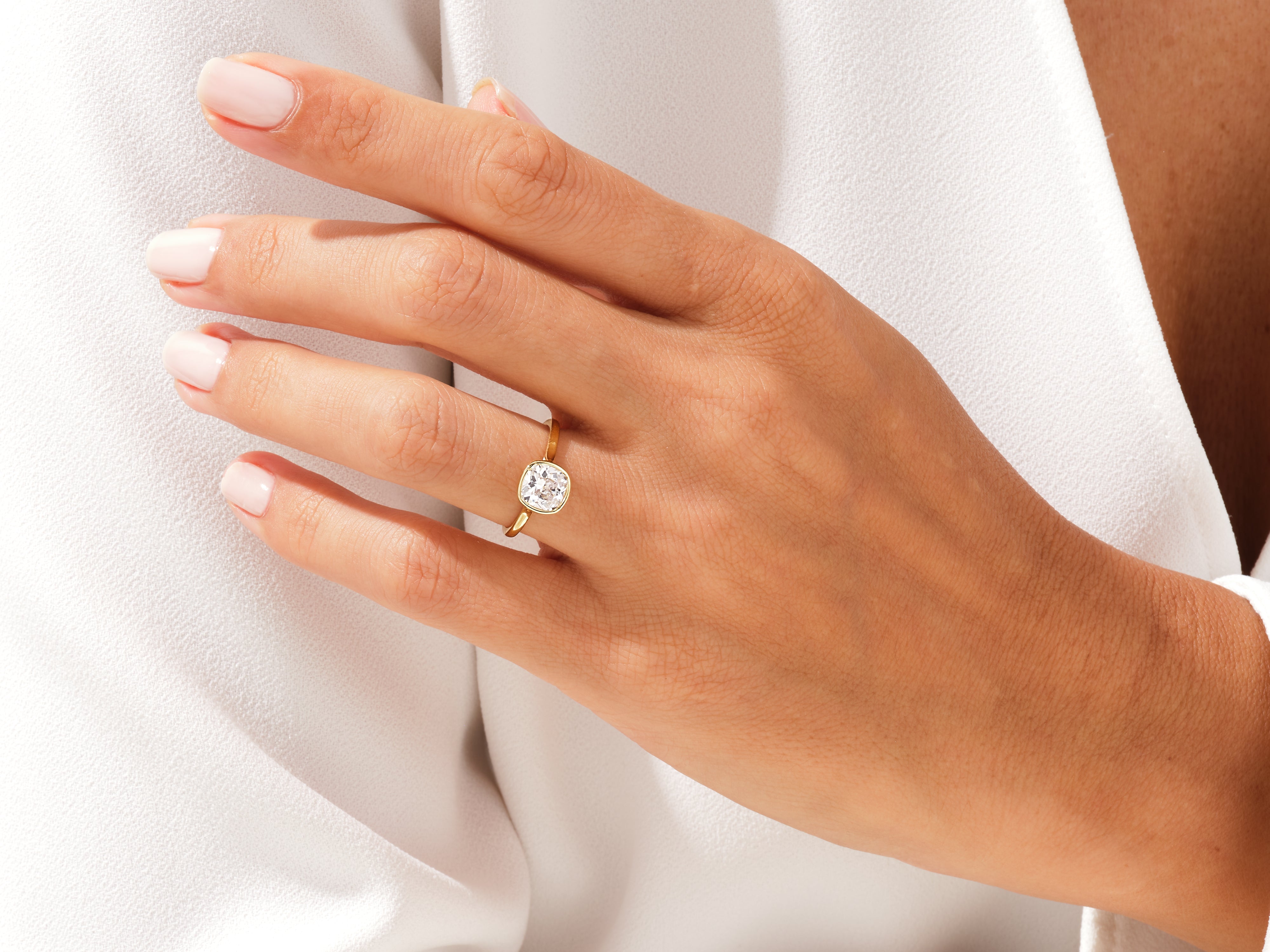 Gold ring with cushion-cut diamond on a woman's hand