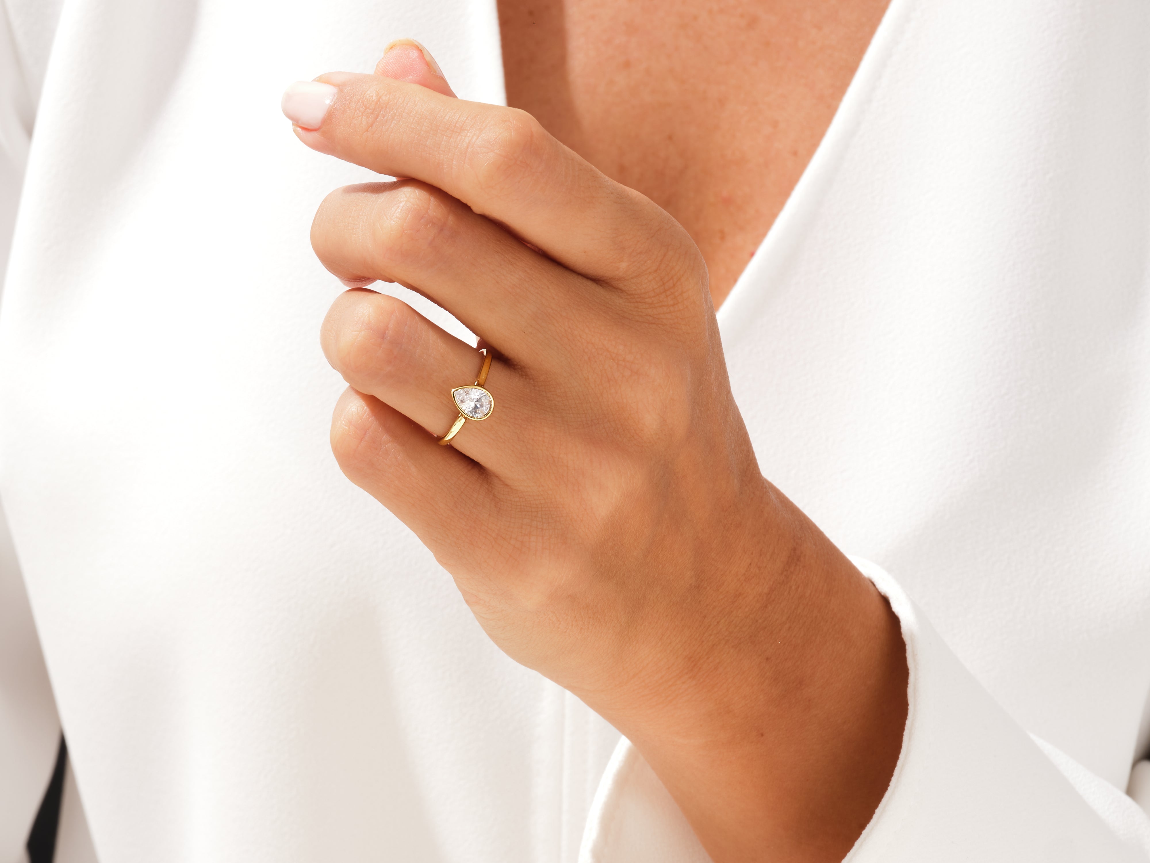 Gold ring with pear-shaped diamond on hand