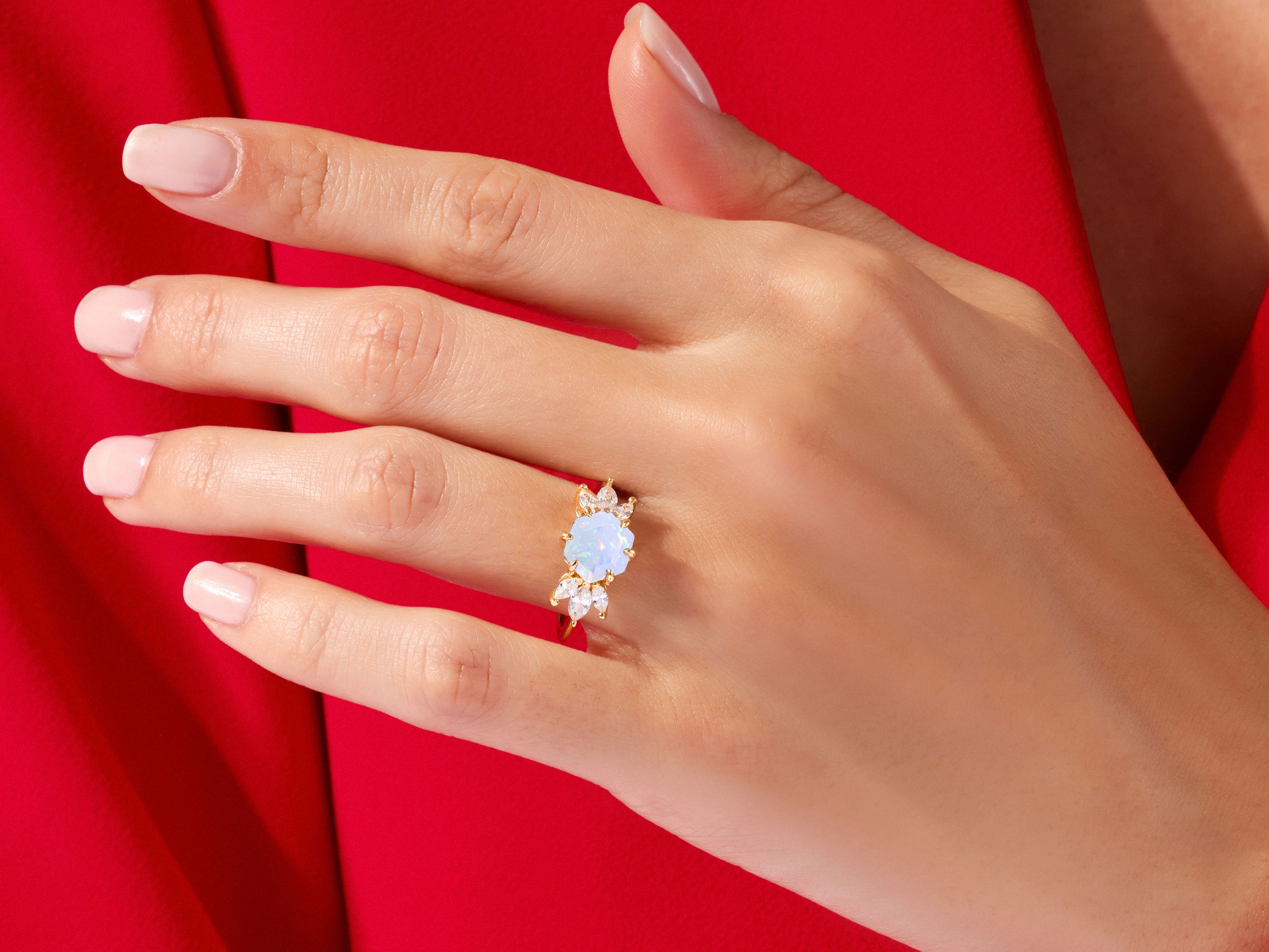 Gold ring with opal and diamond accents on a hand