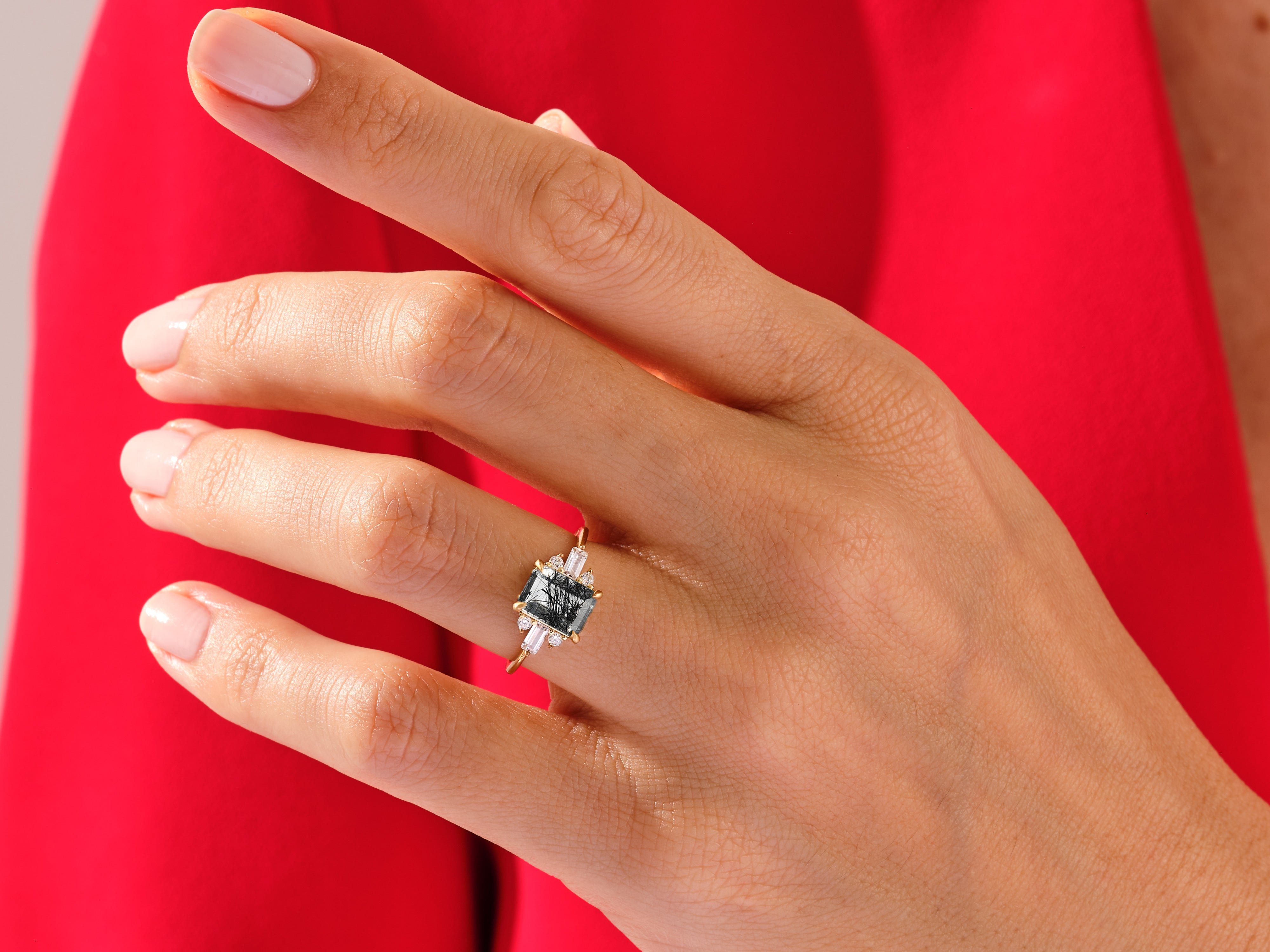 Emerald cut gemstone ring with baguette diamonds on a hand
