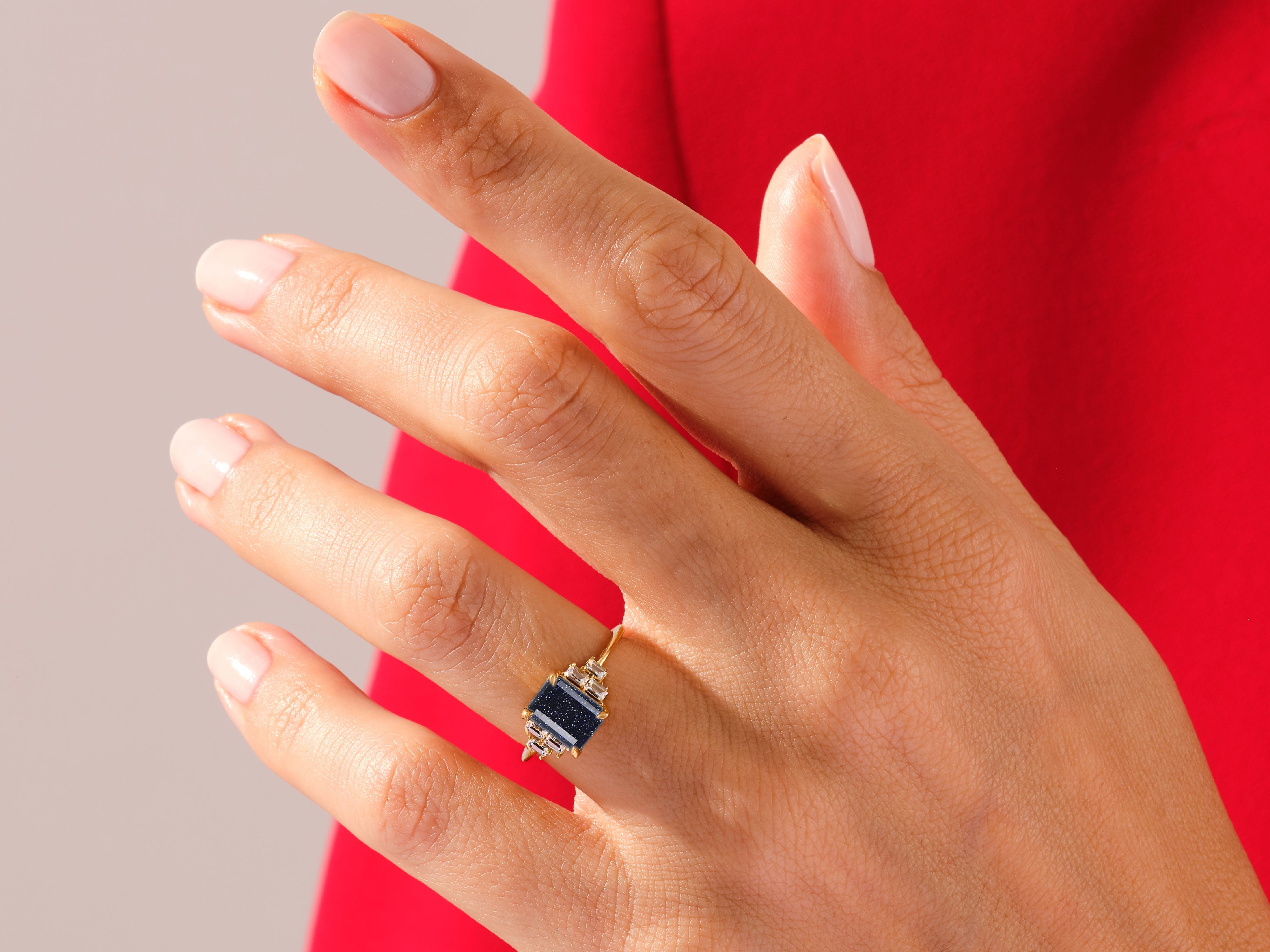 Gold ring with blue gemstone and diamonds on a hand