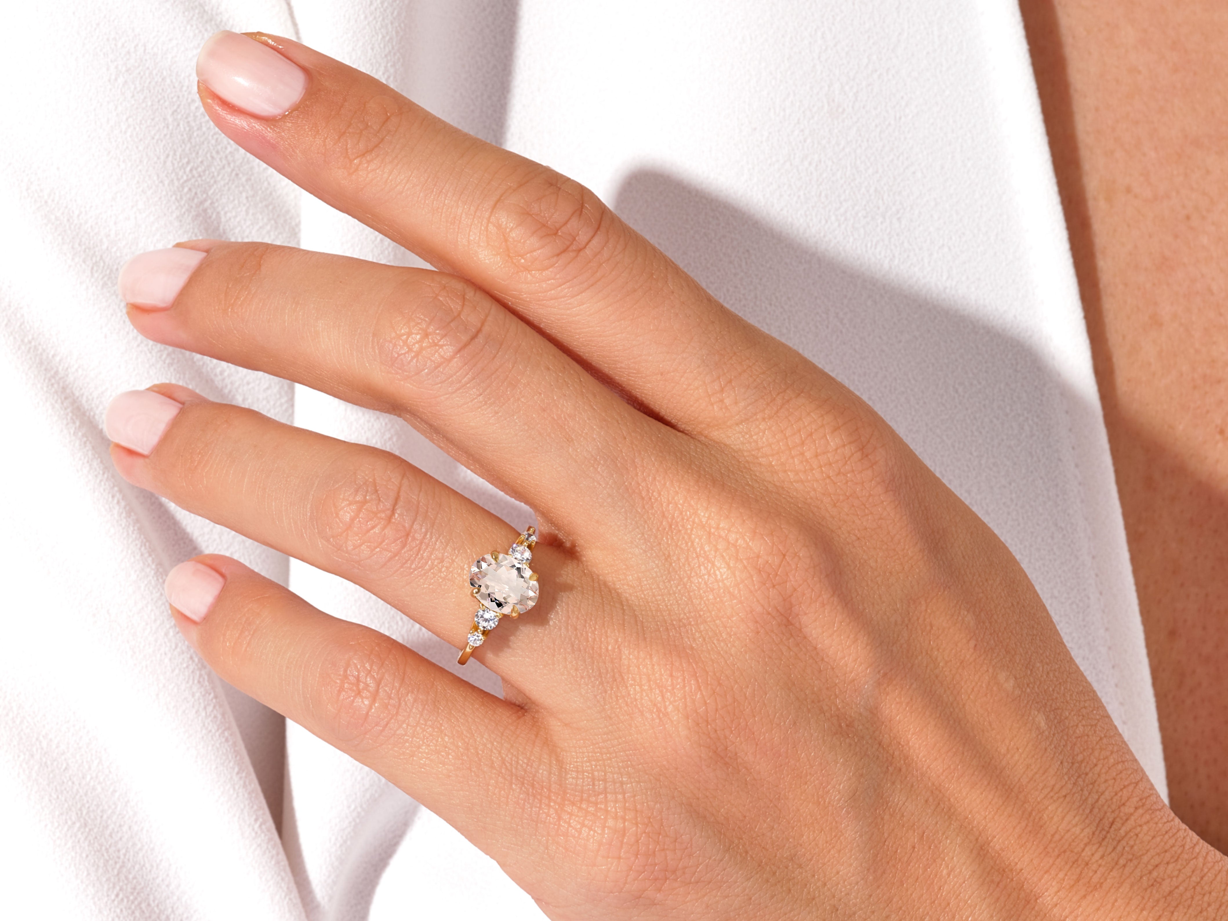 Gold ring with oval diamond and side stones on hand