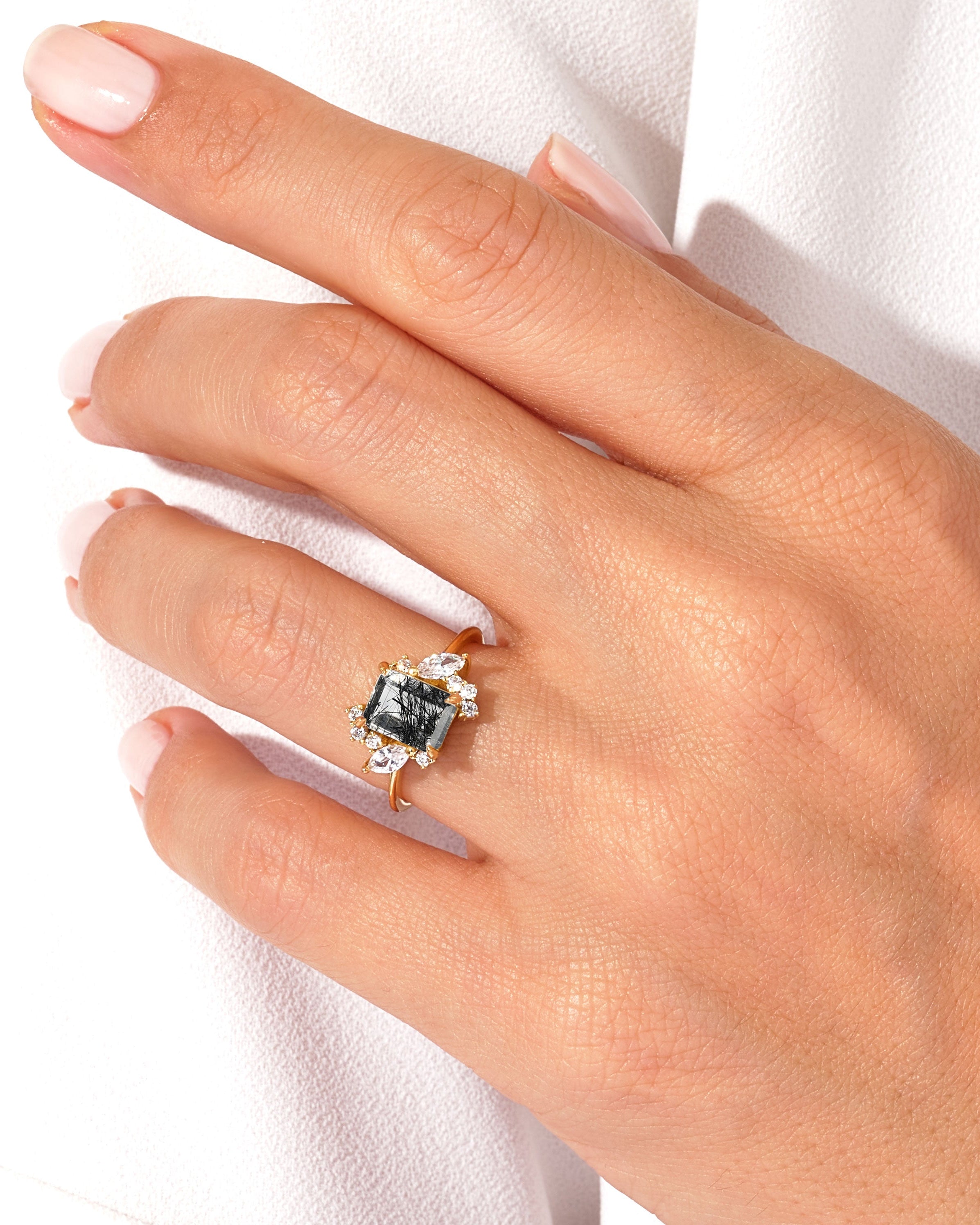 Gold ring with dark gemstone and diamonds on a hand