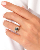 Gold ring with dark gemstone and diamonds on a hand