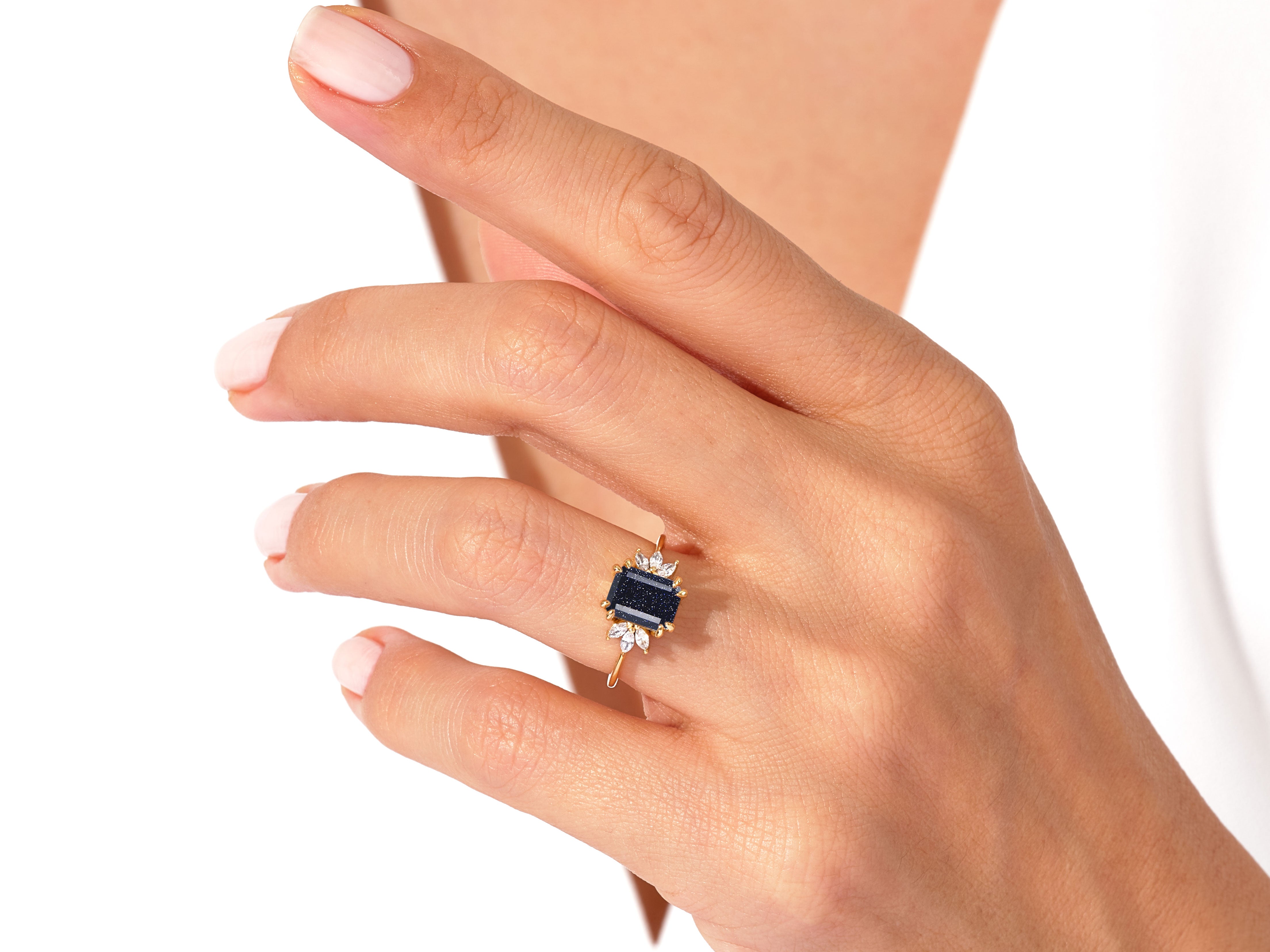 Gold ring with dark blue gemstone and diamonds on a woman's finger
