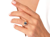 Emerald cut sapphire ring with diamond accents on a woman's hand