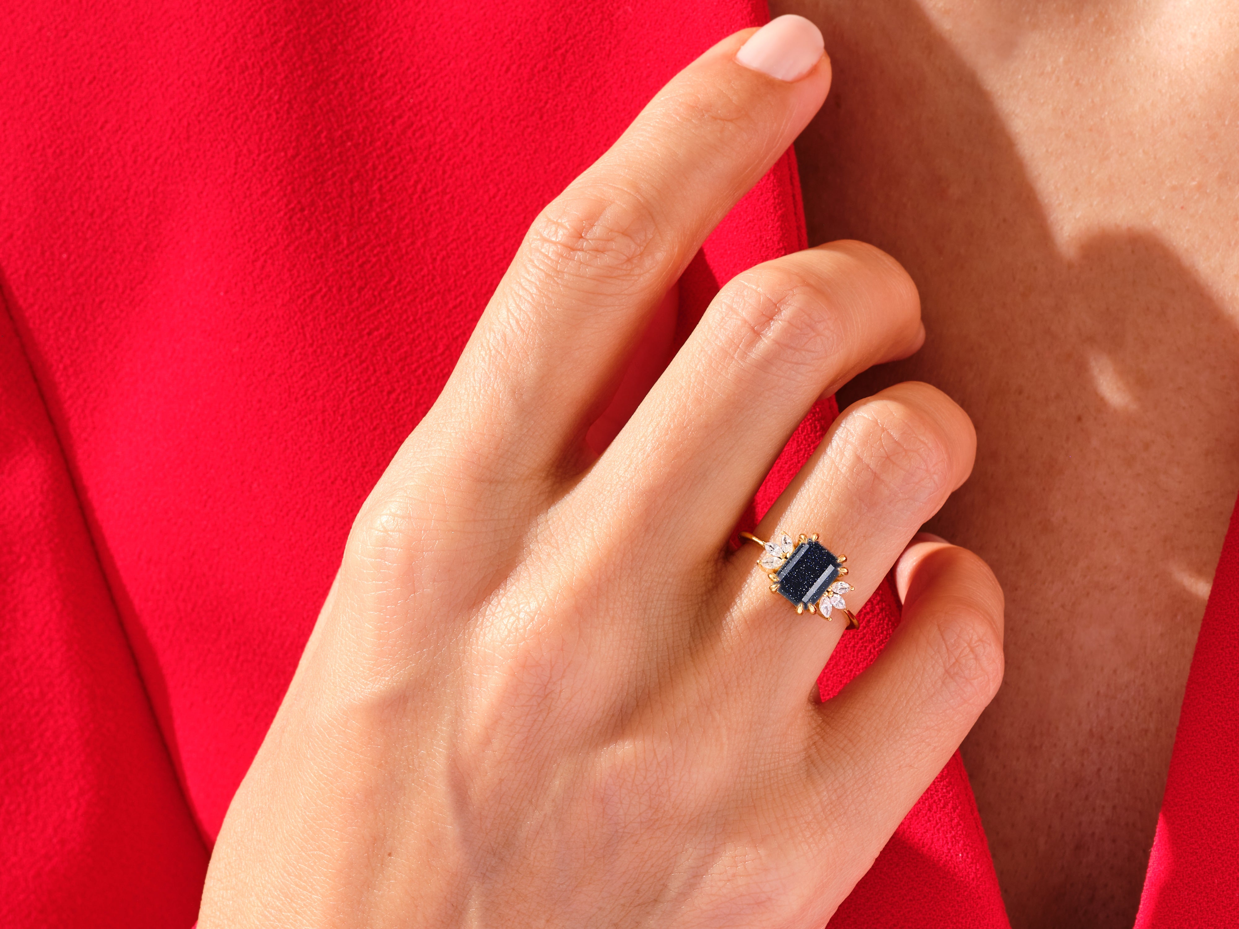 Gold ring with dark blue stone and diamonds on hand