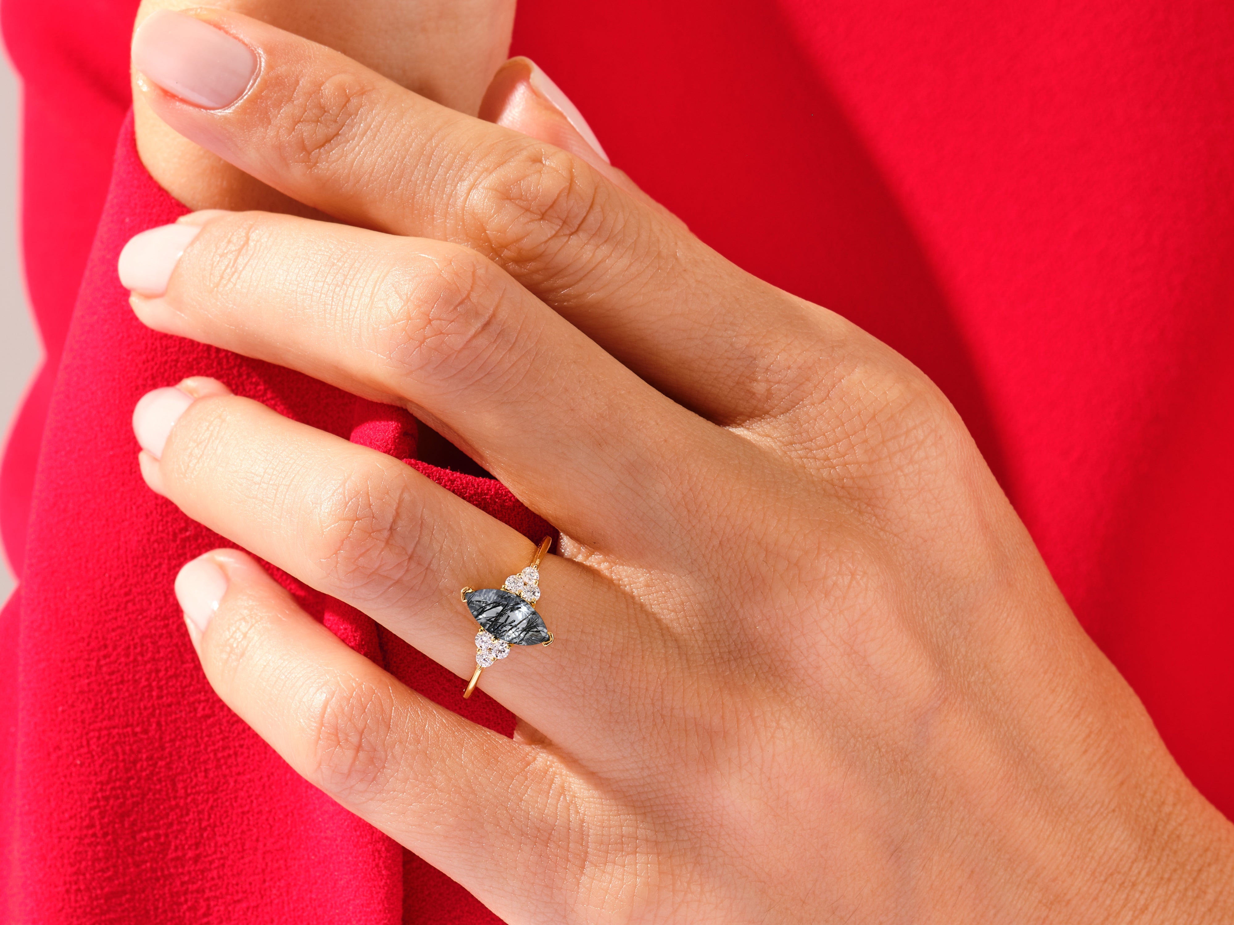 Gold ring with grey gemstone and diamonds on a hand
