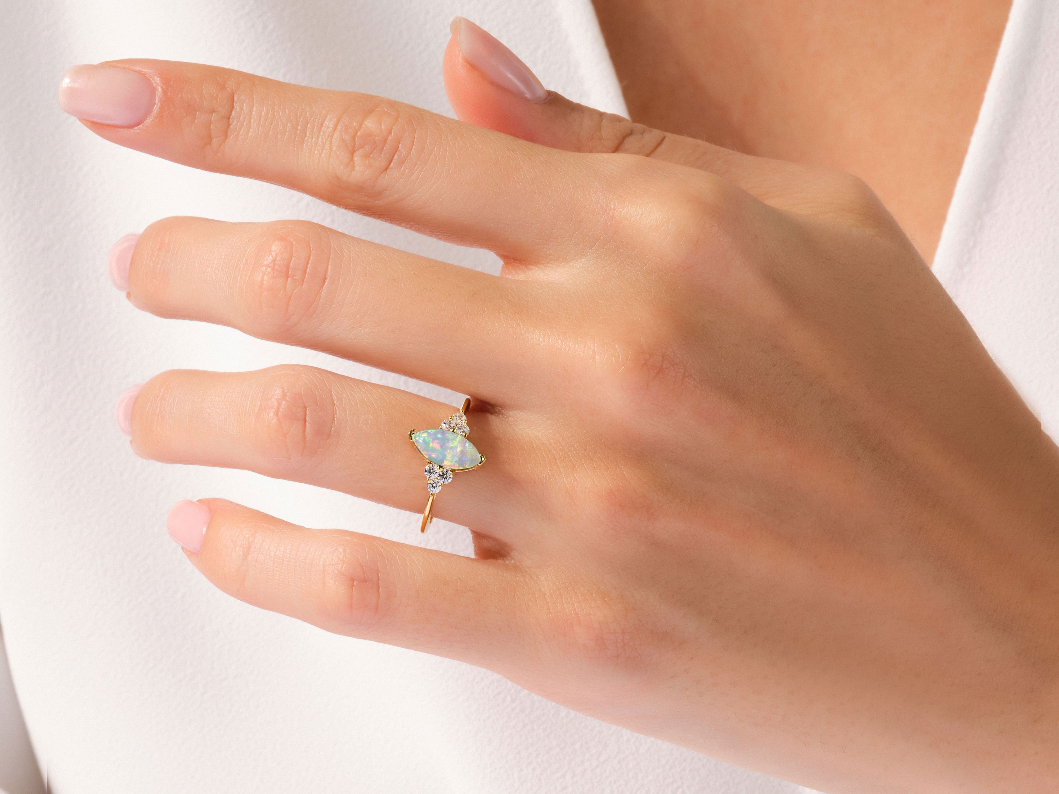 Gold marquise opal and diamond ring on a woman's finger