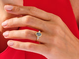 Gold ring with dark gemstone and diamonds on a hand