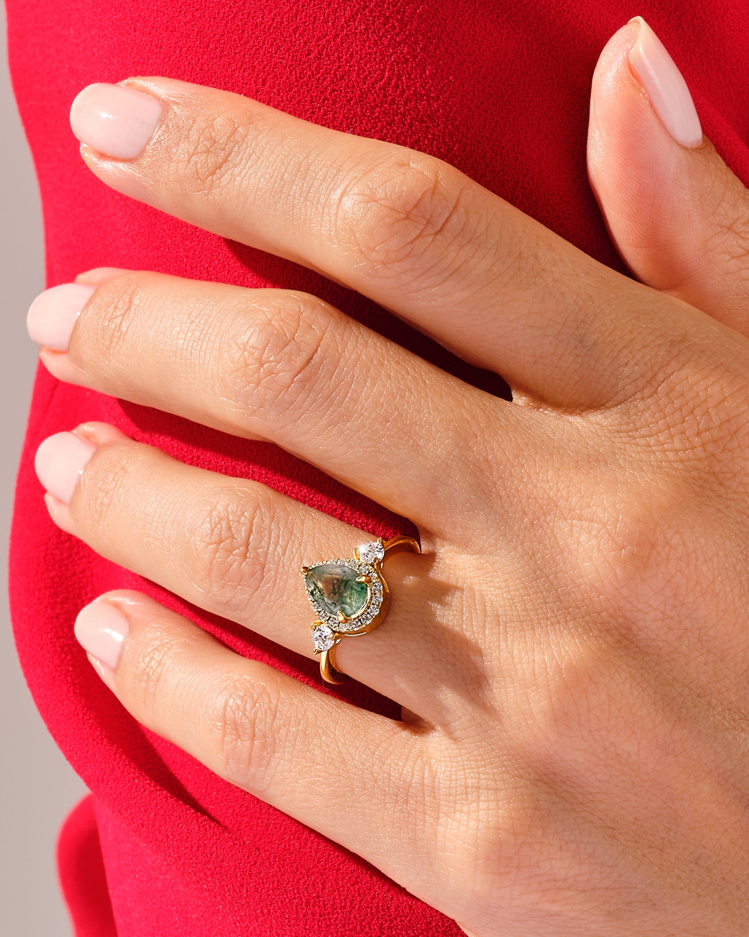 Gold ring with green gemstone and diamonds on hand