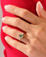 Gold ring with green gemstone and diamonds on hand