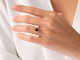 Gold ring with dark blue gemstone and diamonds on a hand
