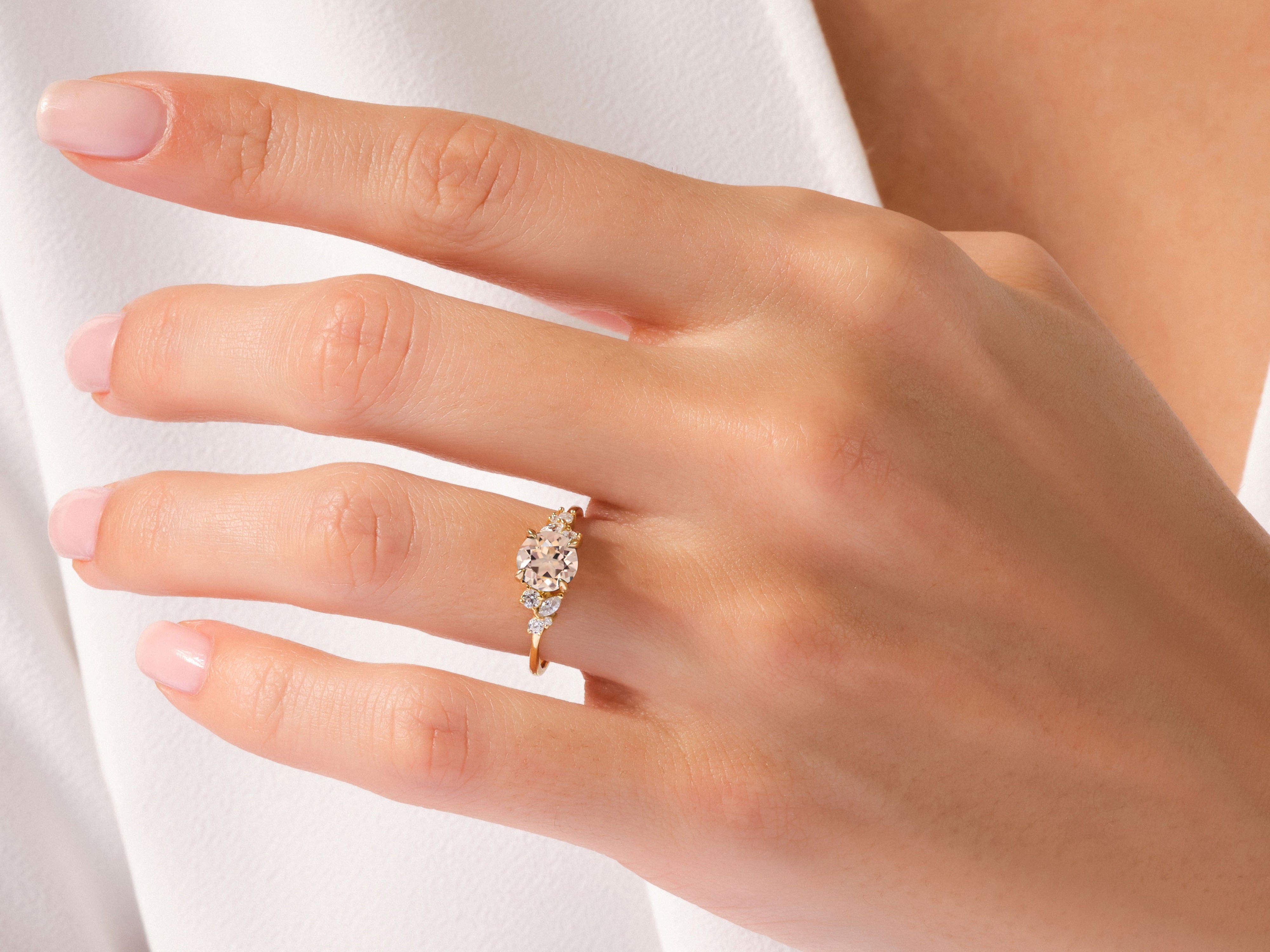 Gold ring with peach and diamond stones on a woman's finger