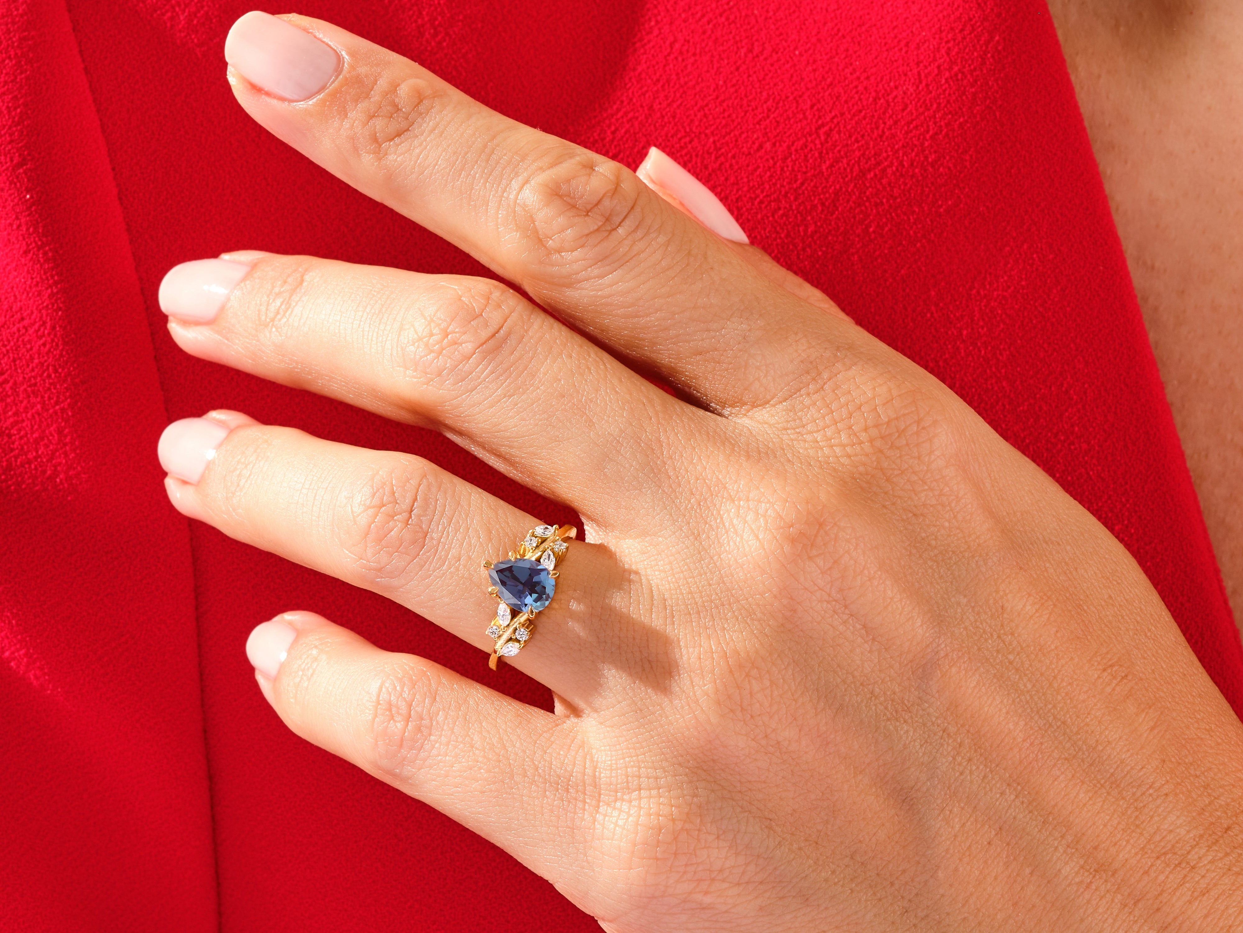 Gold ring with blue gemstone and diamonds on a hand