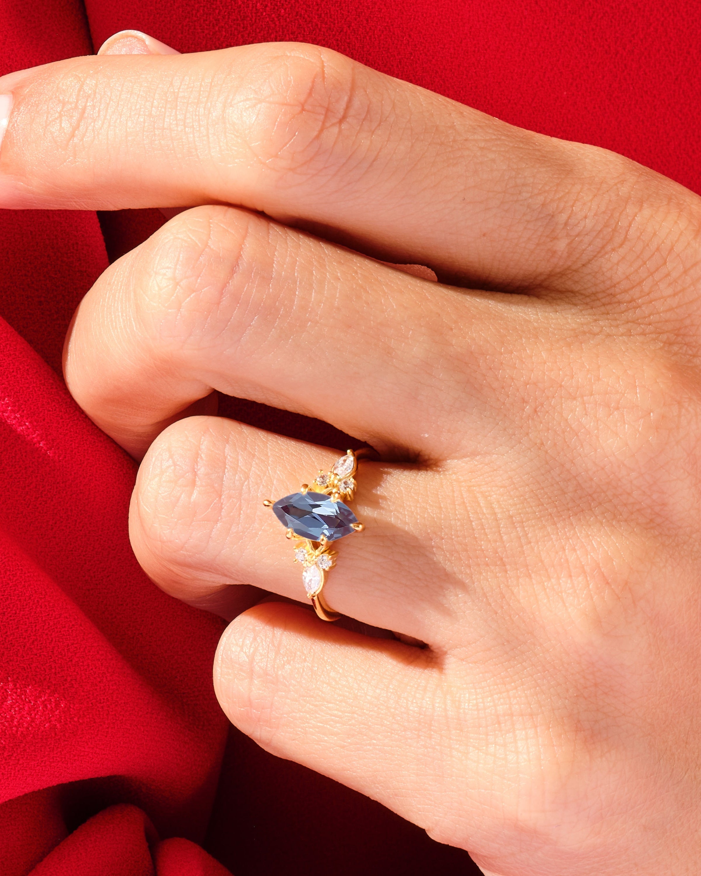 Gold ring with blue marquise gemstone and diamonds on hand