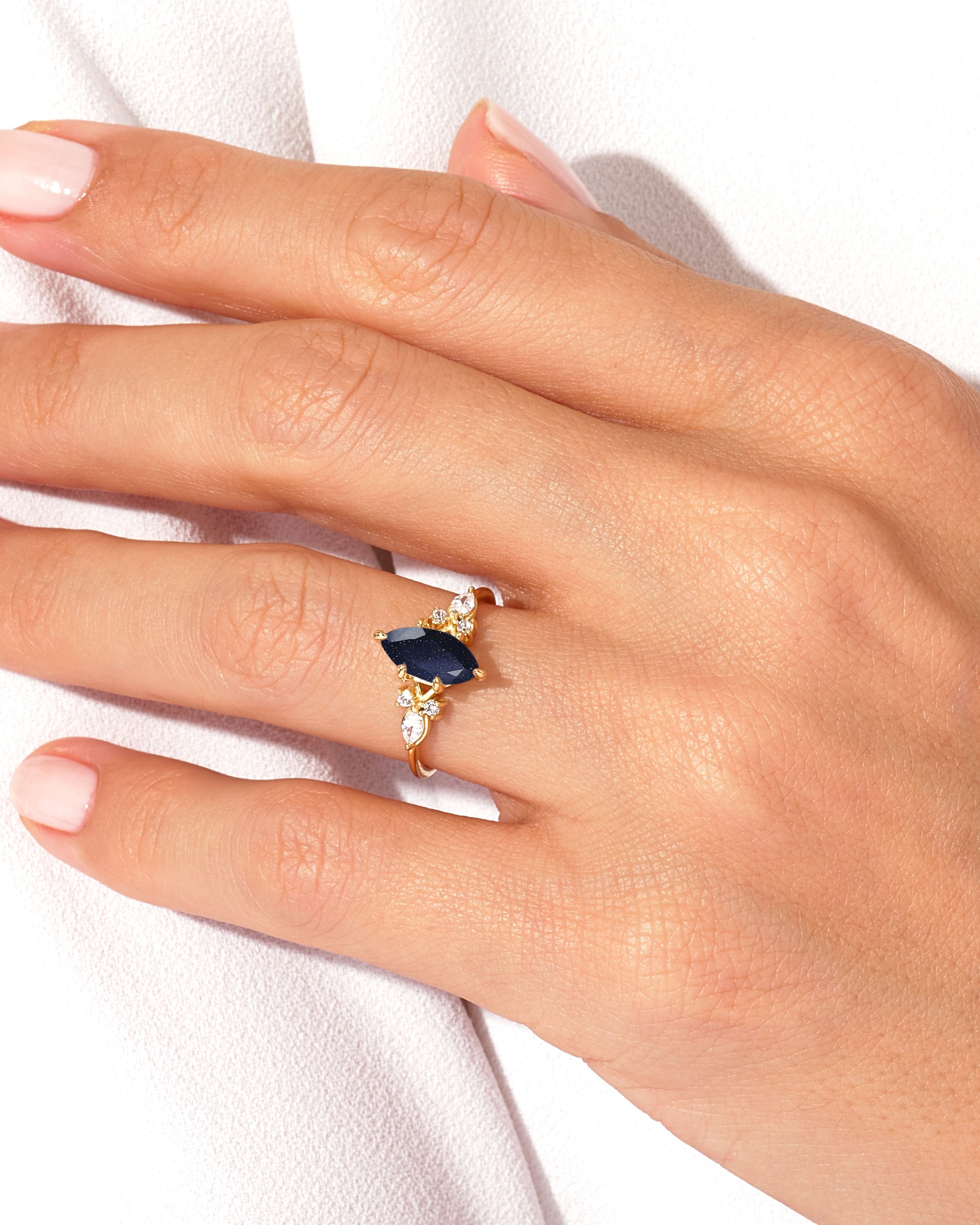 Gold marquise sapphire ring with diamond accents on hand
