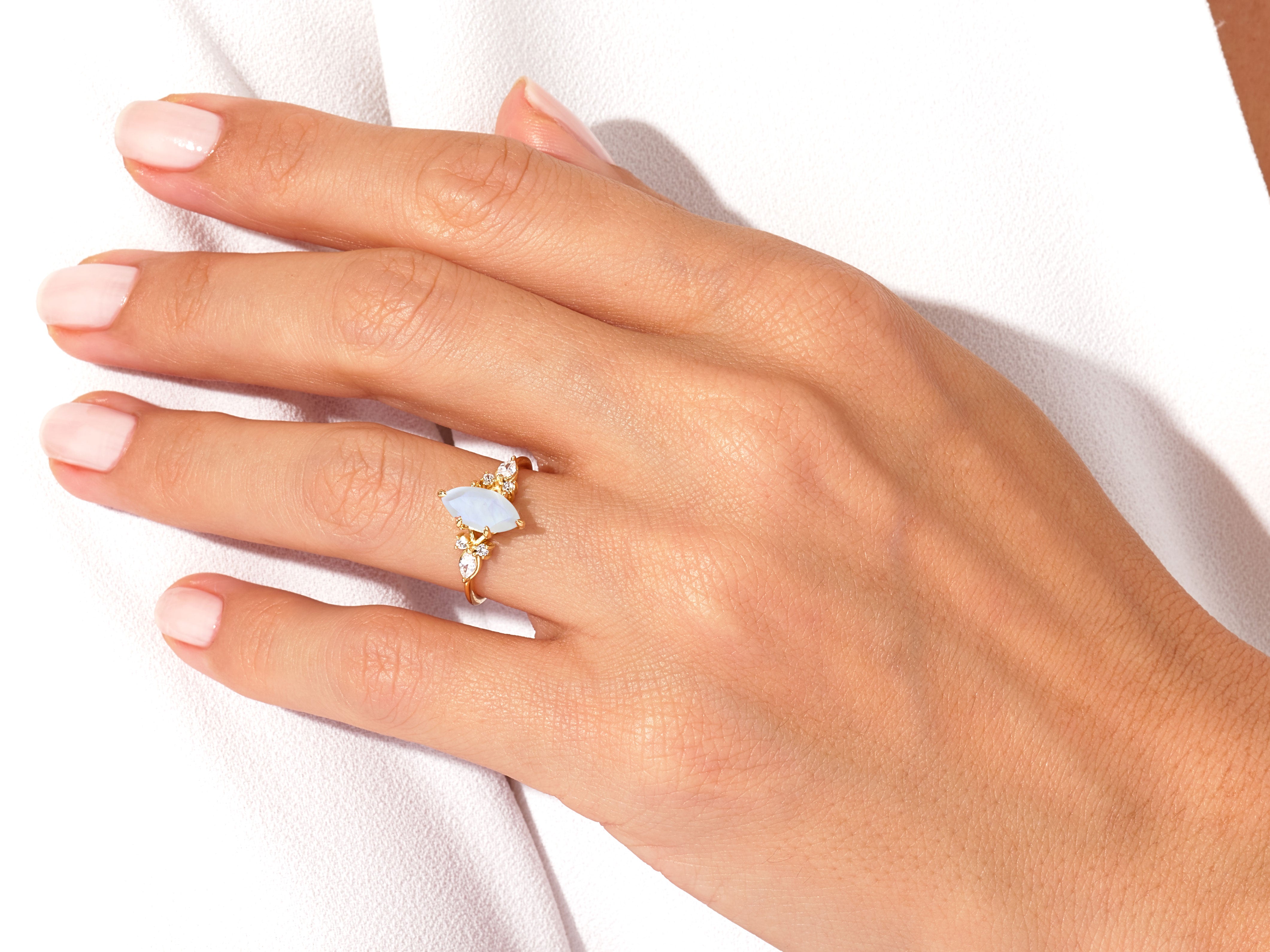 Gold marquise opal ring with diamonds on a hand