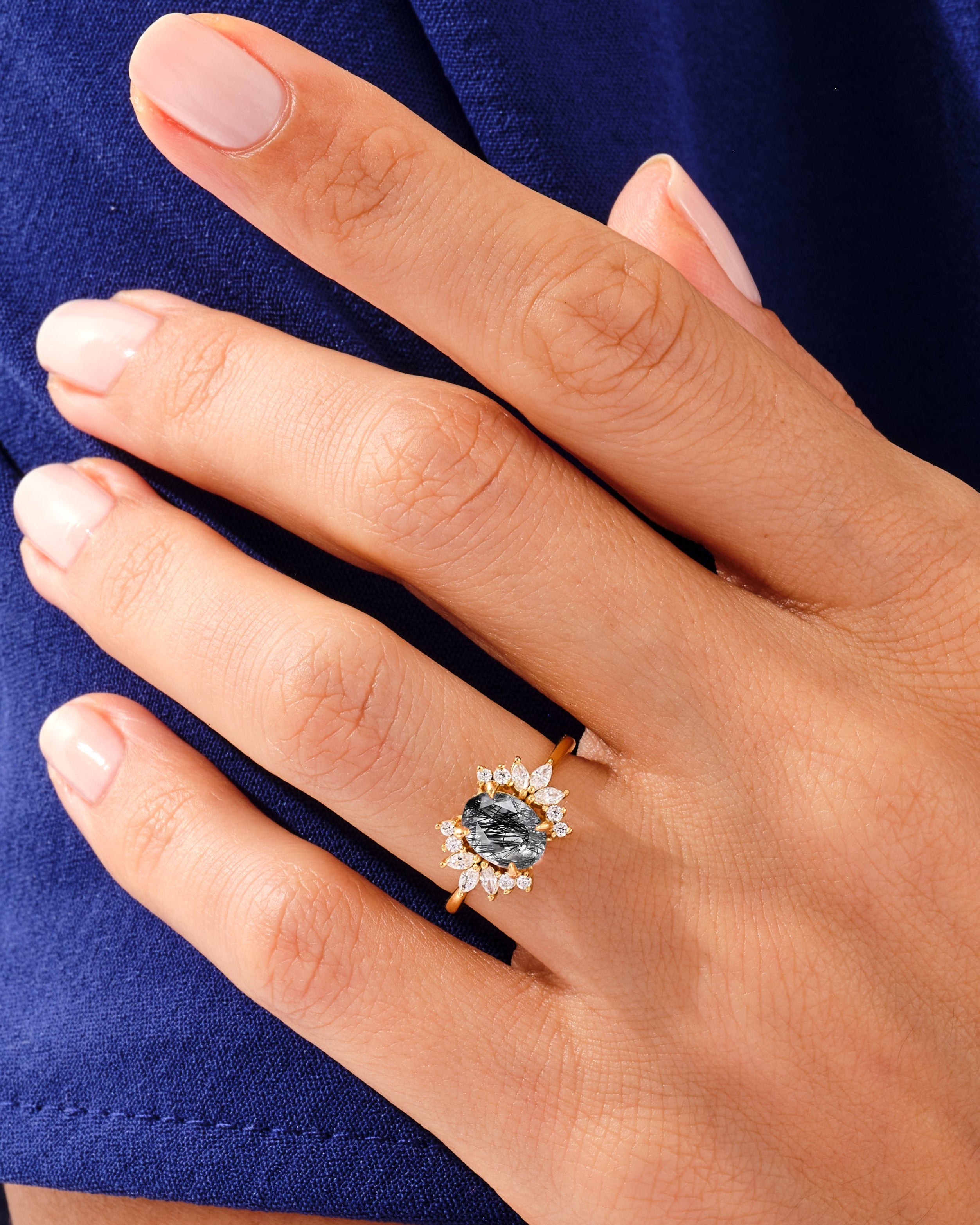 Gold ring with black rutile quartz and diamonds on a hand
