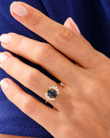 Gold ring with oval blue stone and diamond accents on hand