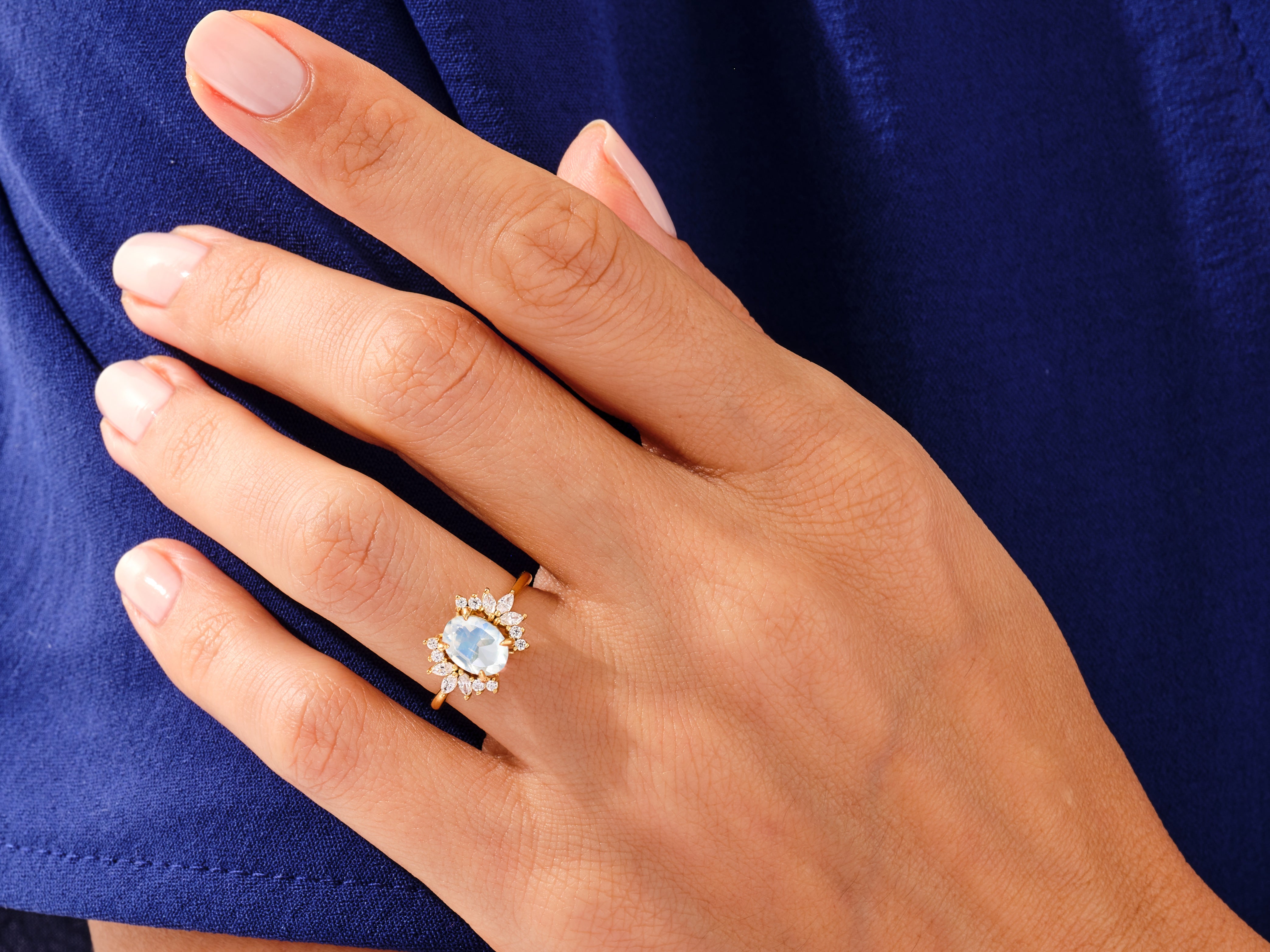 Gold ring with oval moonstone and diamond accents on hand
