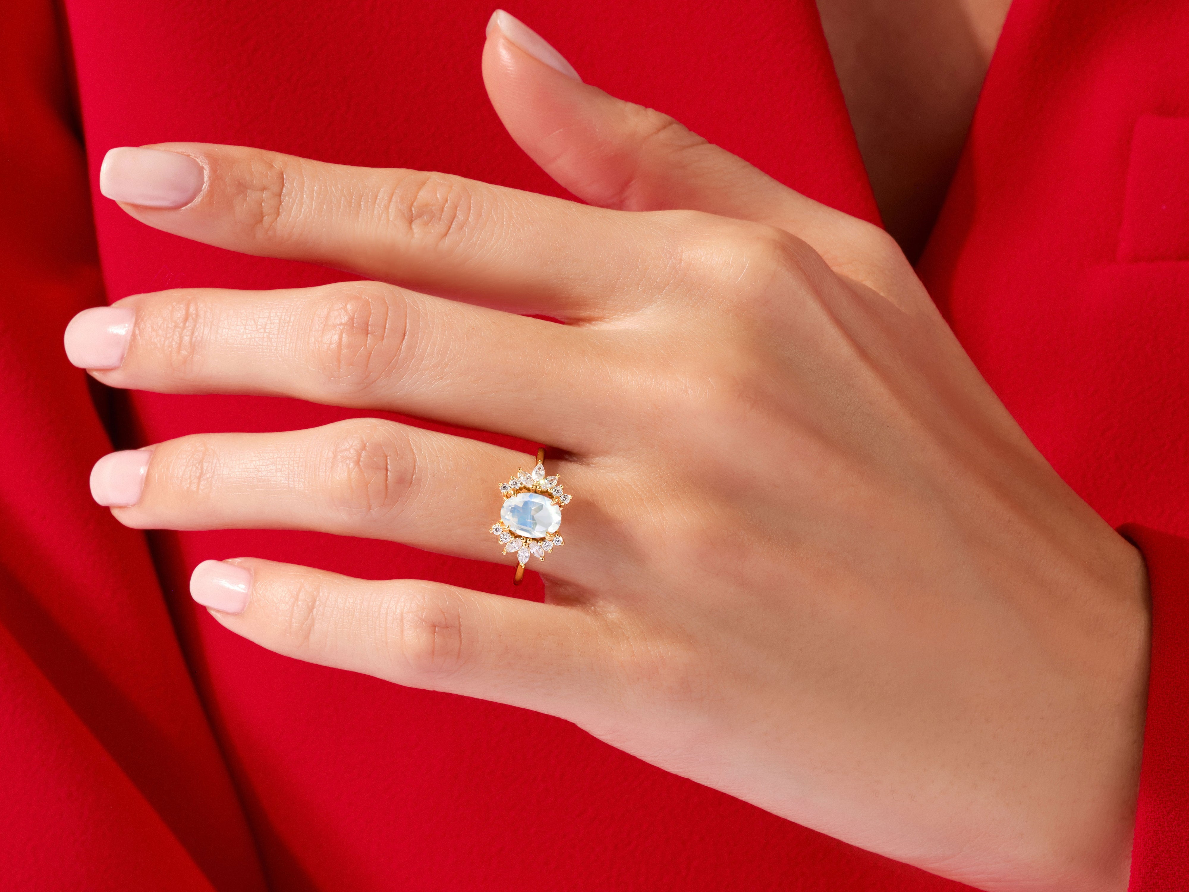 Gold ring with oval moonstone and diamond halo on a hand