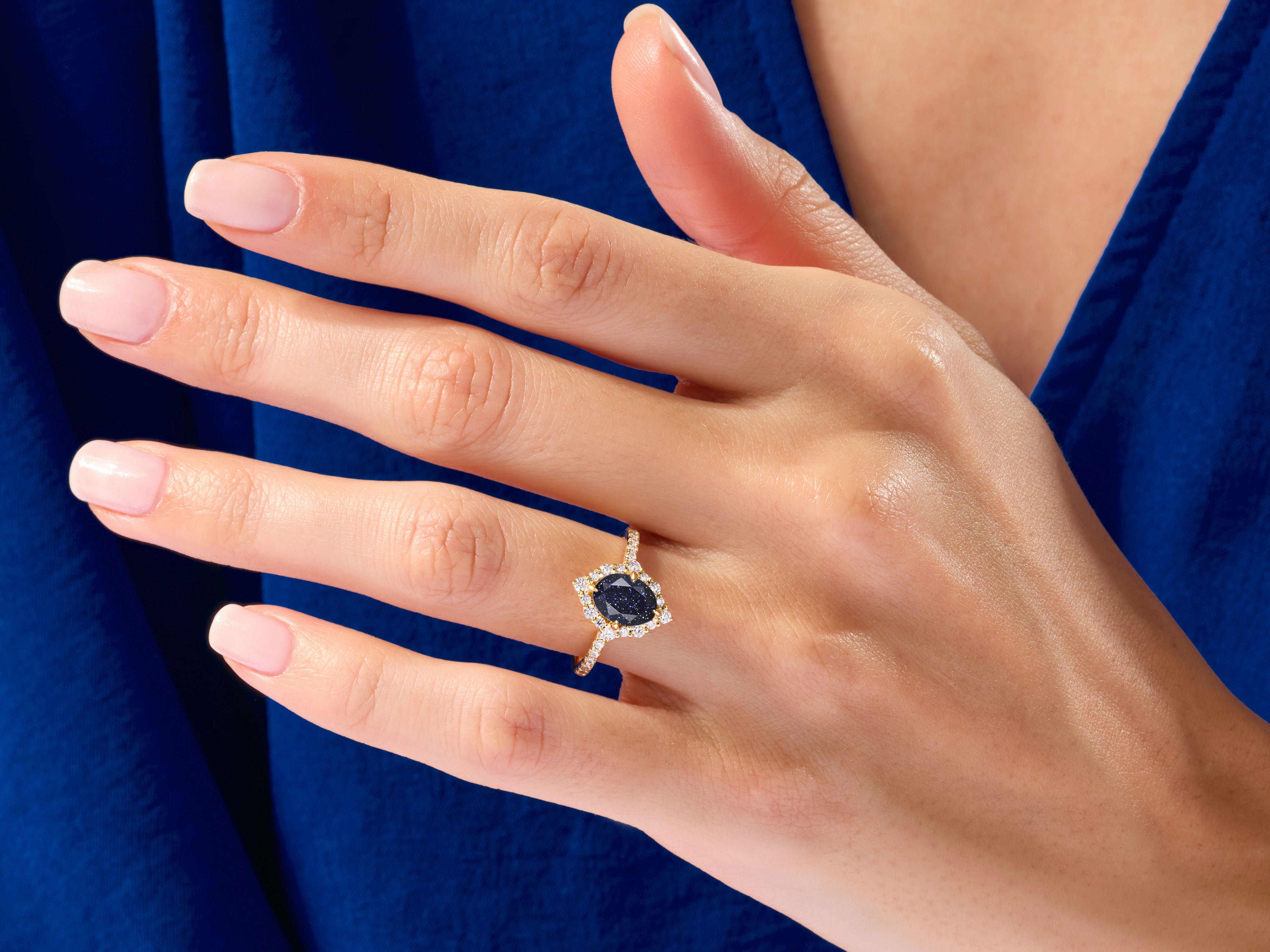 Gold ring with blue stone and diamonds on hand