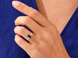 Gold ring with dark gemstone and diamonds on a woman's hand