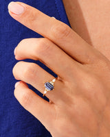 Emerald cut sapphire ring with diamond accents on a hand