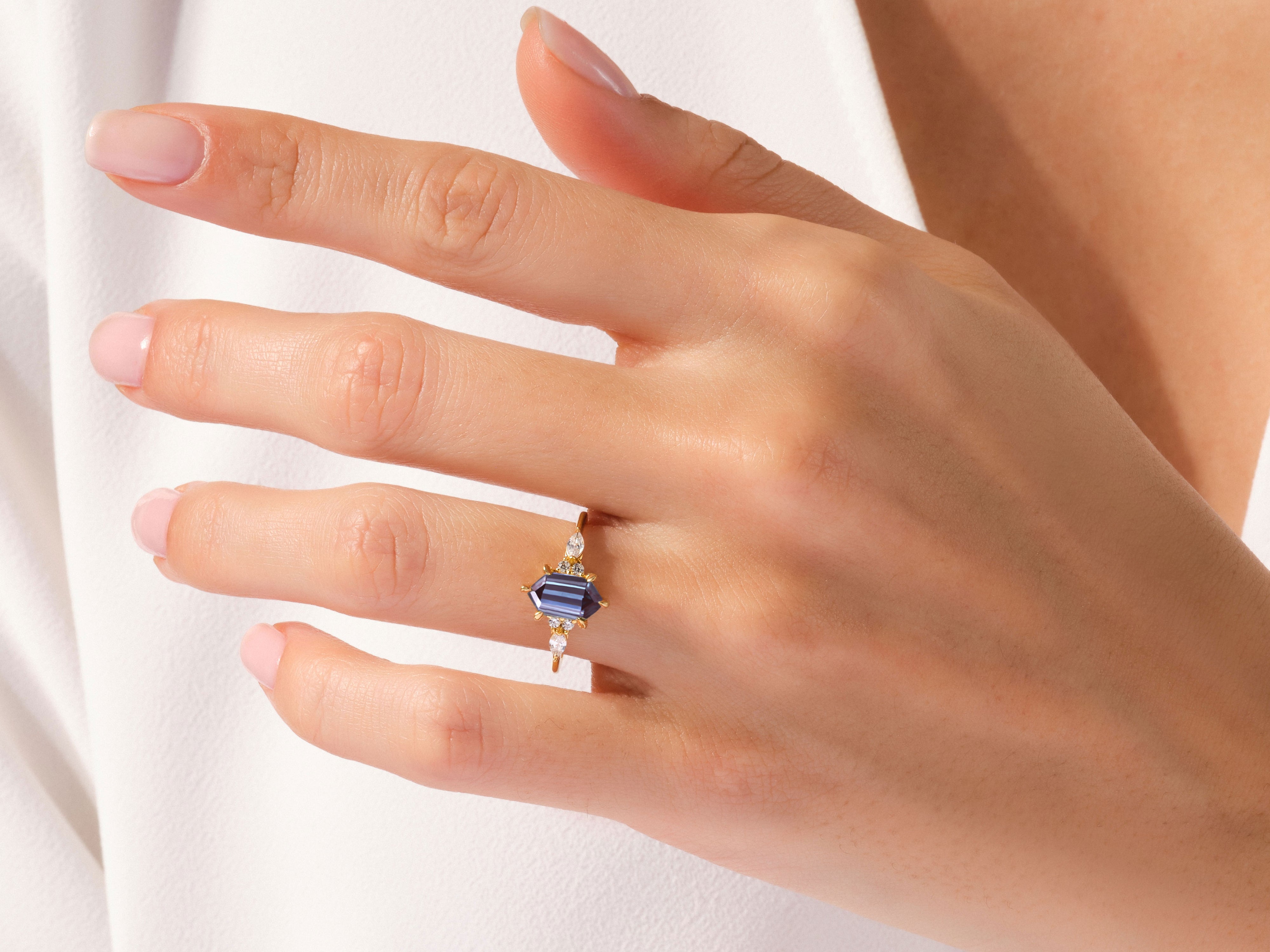 Elegant gold ring with blue gemstone and diamonds on a hand