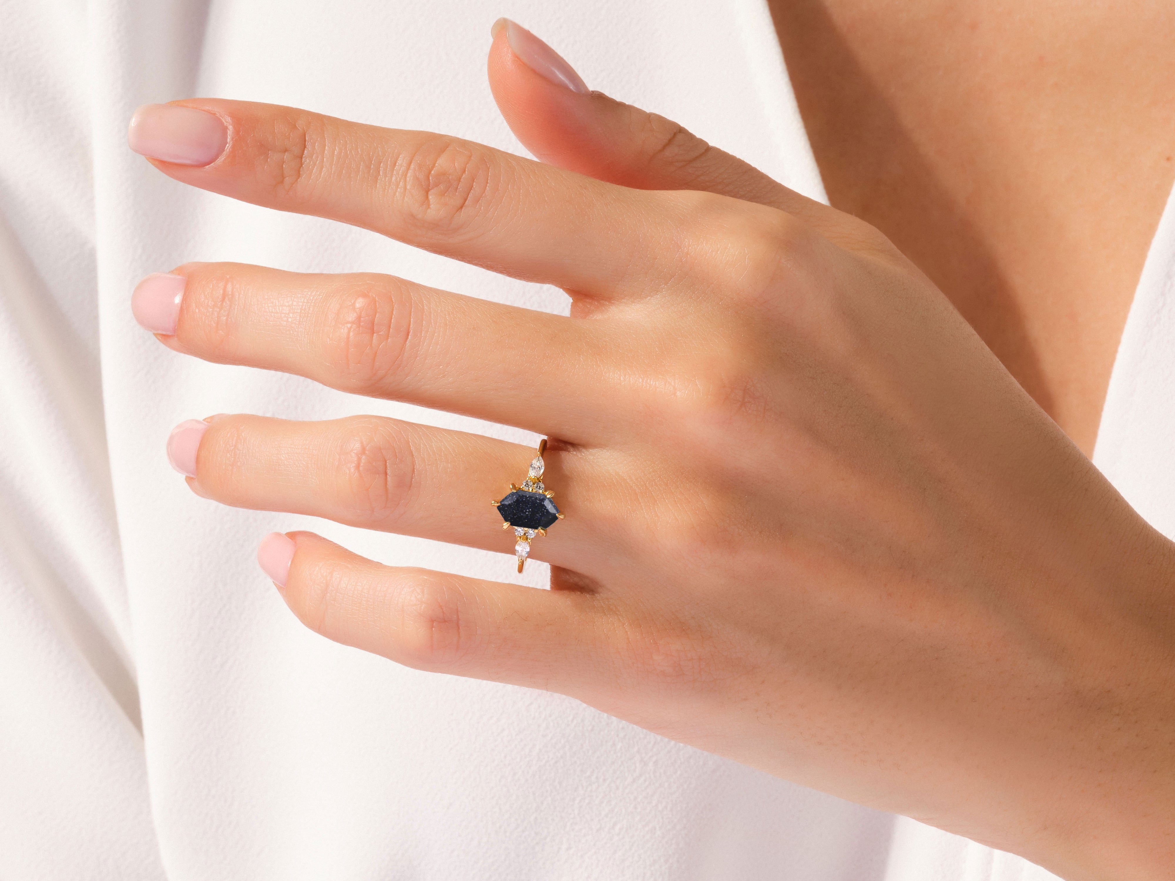 Hexagonal dark blue gemstone ring with diamonds on a gold band