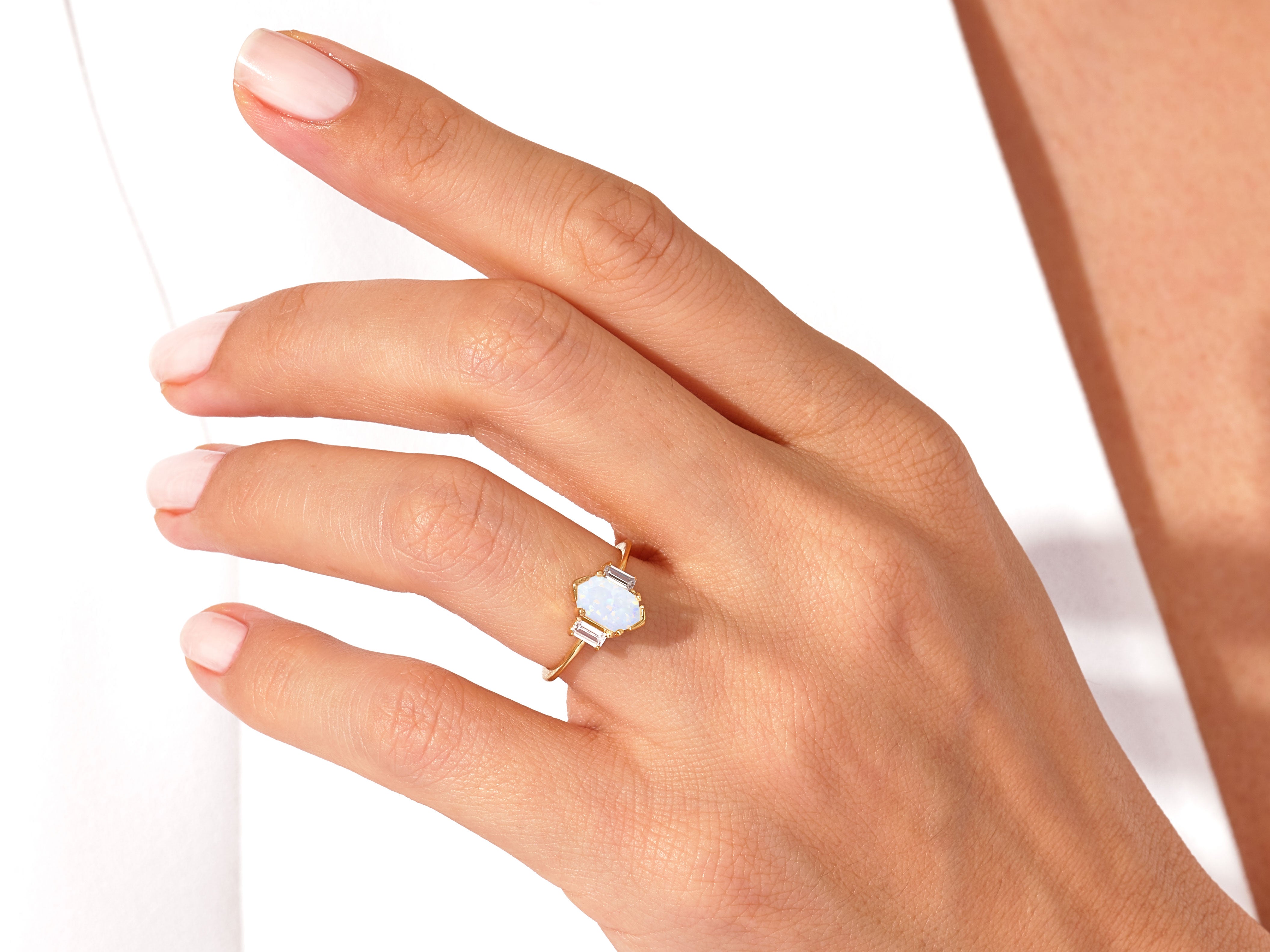 Gold ring with opal and baguette diamonds on a hand