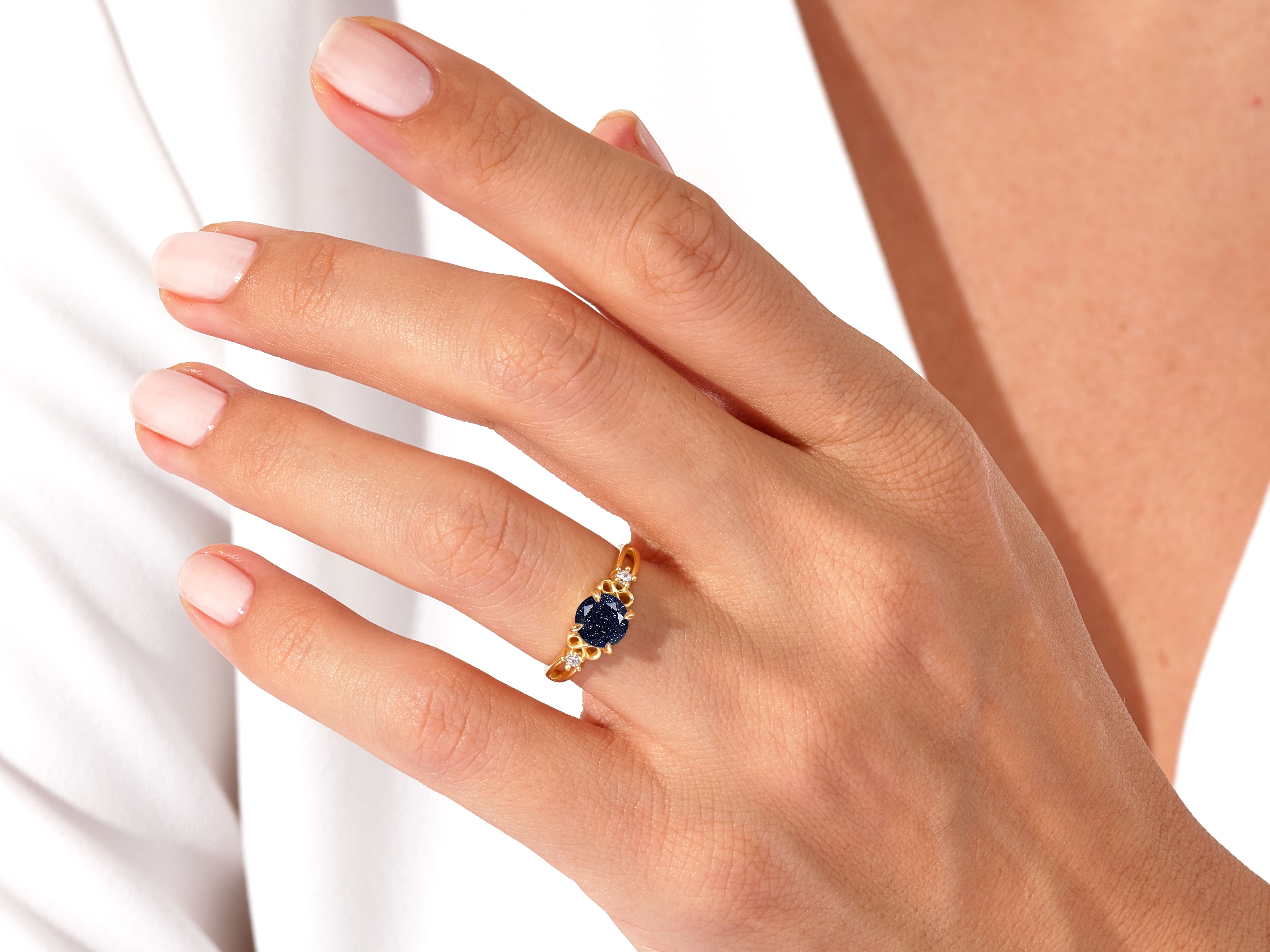 Gold ring with blue stone and diamonds on a woman's finger
