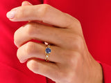 Gold ring with blue gemstone and diamonds on hand