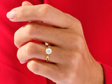 Gold ring with opal and diamonds on a hand