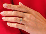 Emerald cut gemstone ring with diamonds on a red background