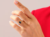Gold ring with dark gemstone and diamonds on a woman's hand