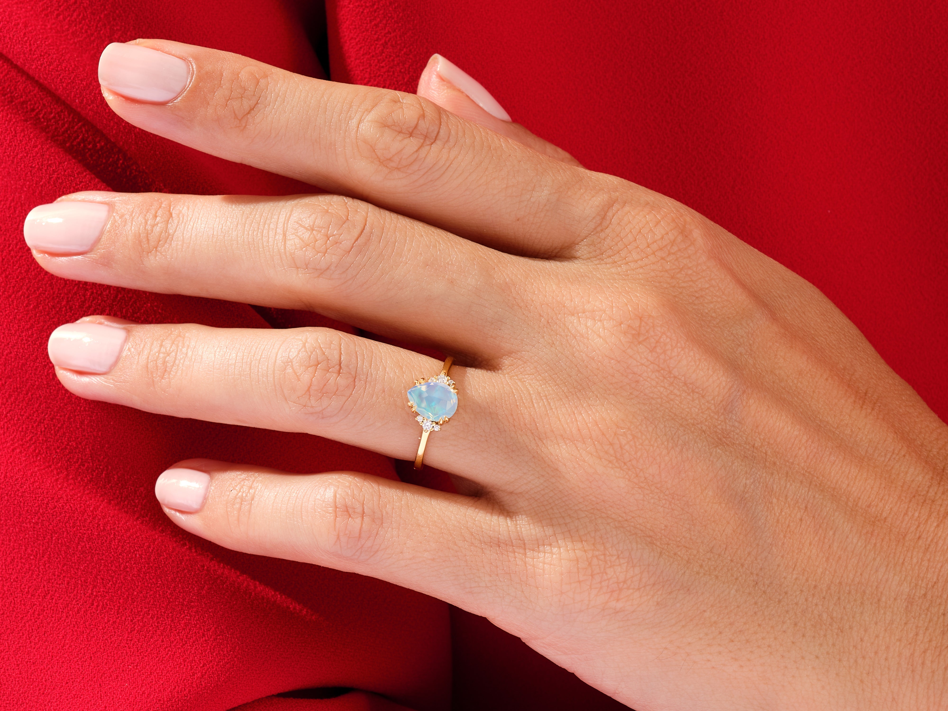 Gold opal ring with diamonds on a hand