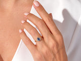 Gold pear-shaped sapphire ring with diamonds on a woman's hand